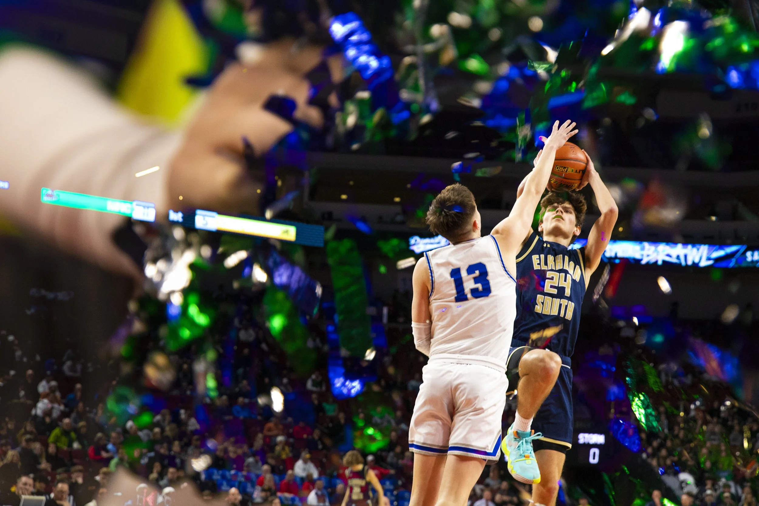 Using an in camera double exposure, A cheerleaders pom-pom is used to frame Millard North's Neal Mosser as he blocks a layup attempt by Elkhorn South's Evan Werner during a Class A state tournament game Wednesday, March 8, 2023, at Pinnacle Bank Aren