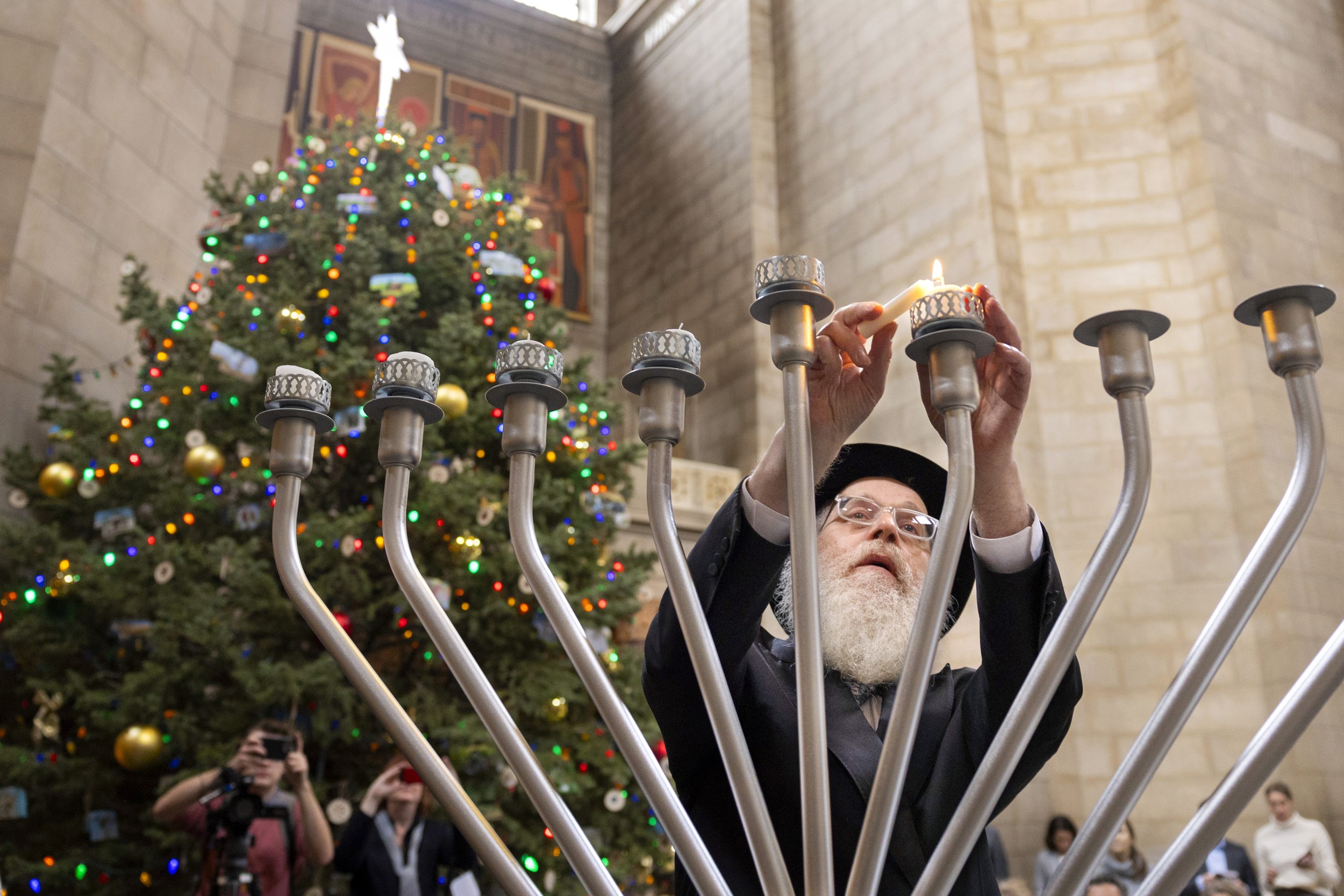  Rabbi Mendel Katzman, Executive Director at Chabad of Nebraska and a member of OPD Chaplains Corps, uses the shamash to light a second candle of the menorah during a ceremony held in the rotunda of the State Capitol on the fifth day of Hanukkah, on 