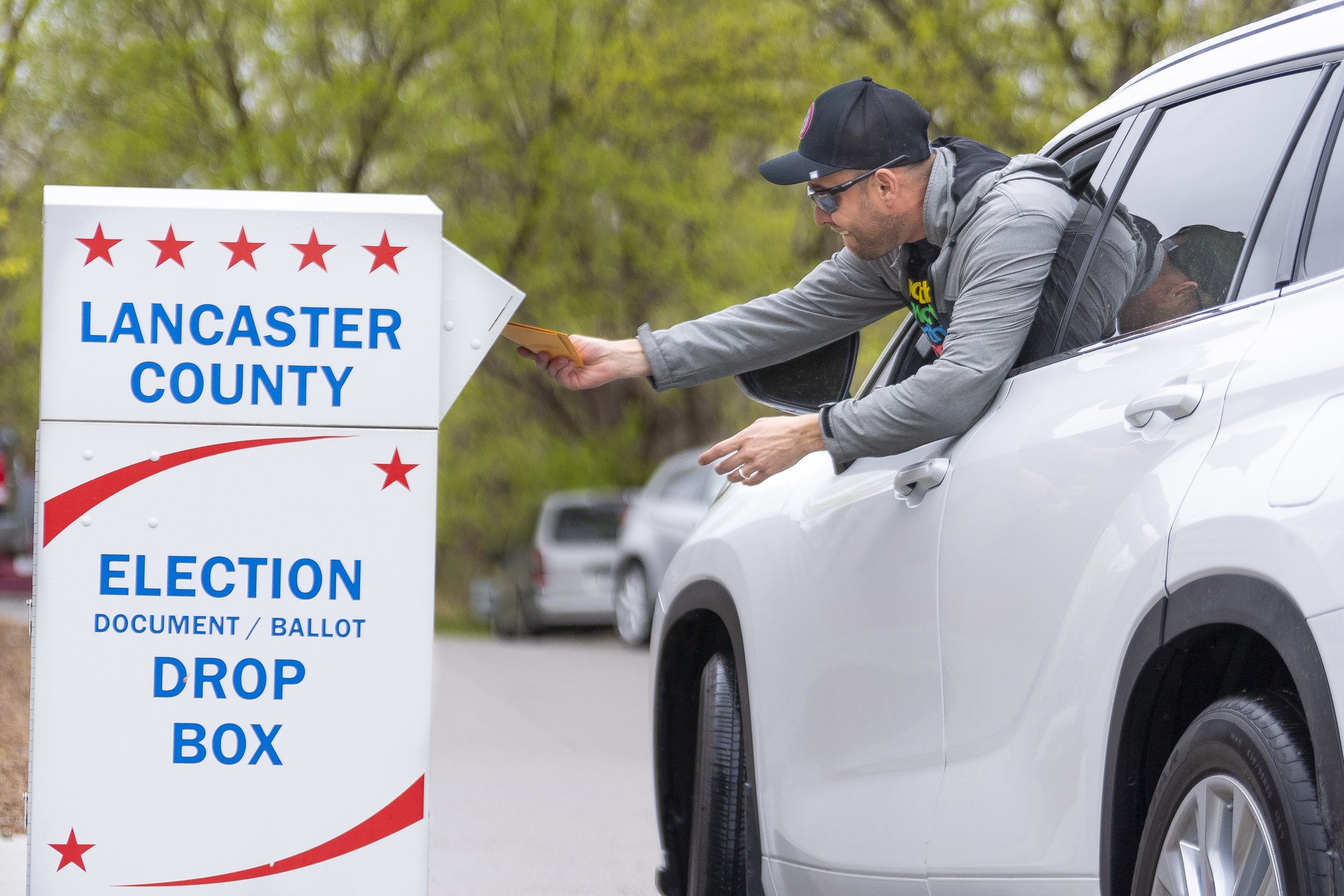  A voter leans out of their car to deposit their ballot at a drop box located outside the north side of the Lancaster County Election office on Friday, April 28, 2023, in Lincoln. 