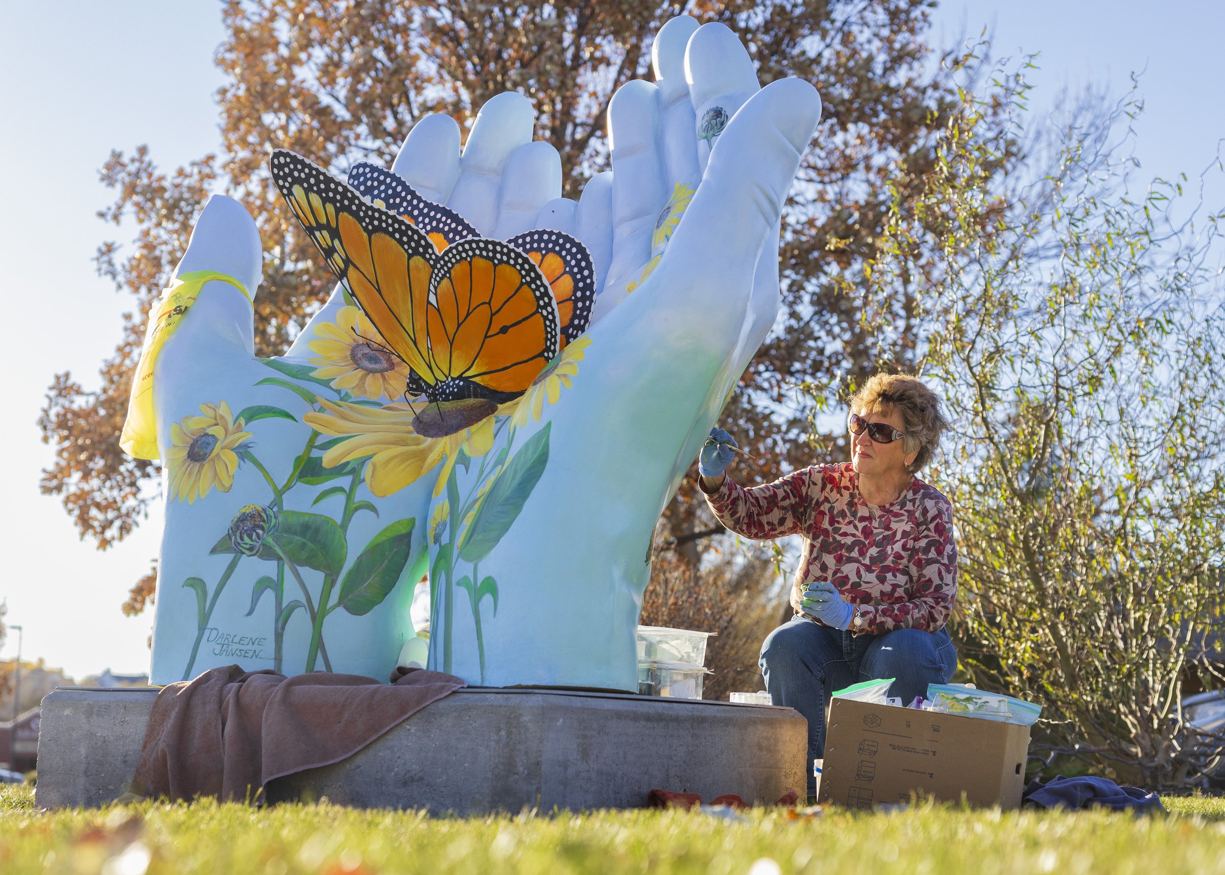  Darlene Jansen, 80,  touches up her Serving Hands art piece titled "Monarch Butterfly" located at 78th and Pioneers outside The Monarch hospice, on Monday, Nov. 13, 2023, in Lincoln.    