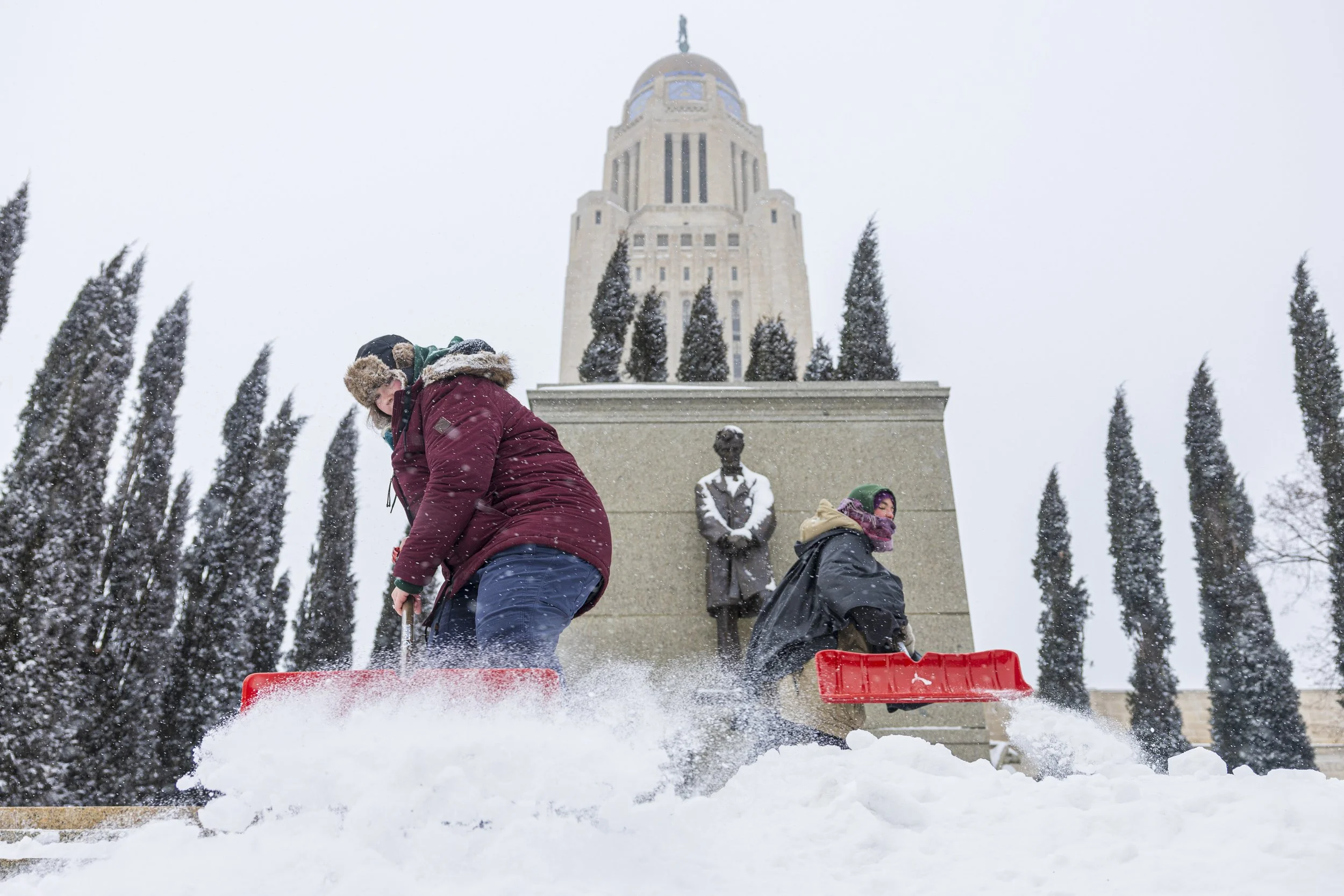  Nebraska State Capitol grounds keepers Lexis Funk (left) and Aud Koch clear the west steps of the Capitol as a winter storm hits Lincoln on Wednesday, Feb. 12, 2025. 
