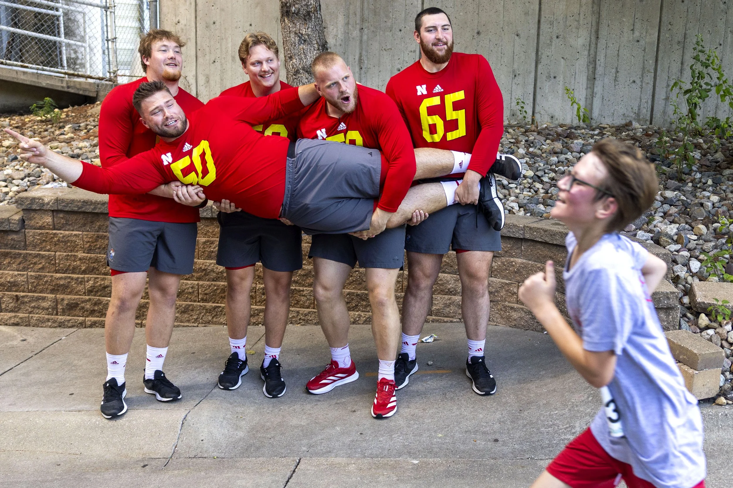  Nebraska offensive linemen Rocco Spindler, center, is held up by his teammates as they cheer on runners and point the way to the finish line of the 5K during the Husker Road Race at Memorial Stadium on Sunday, July 20, 2025, in Lincoln. 