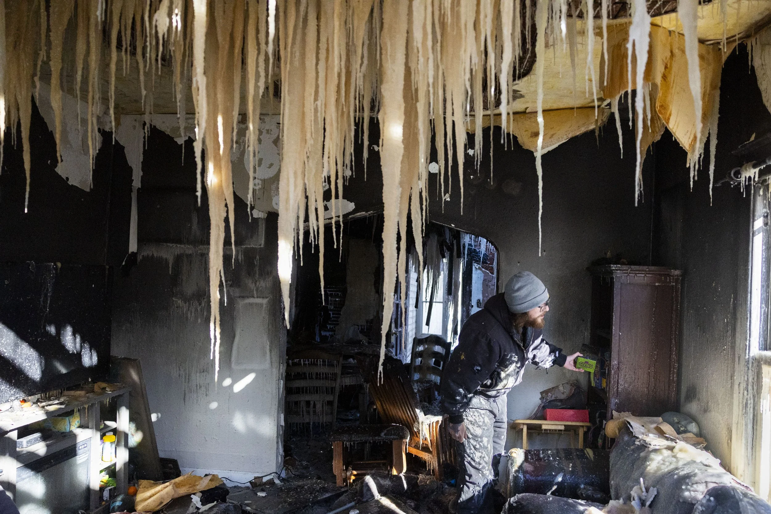  As icy stalactites hang from the ceiling, the Downs neighbor, Macoy Fergus, looks for the family's  look for personal effects inside inside of the Downs home near 25th and L street, which was destroyed in Tuesday's fire, on Thursday, Feb. 20, 2025, 