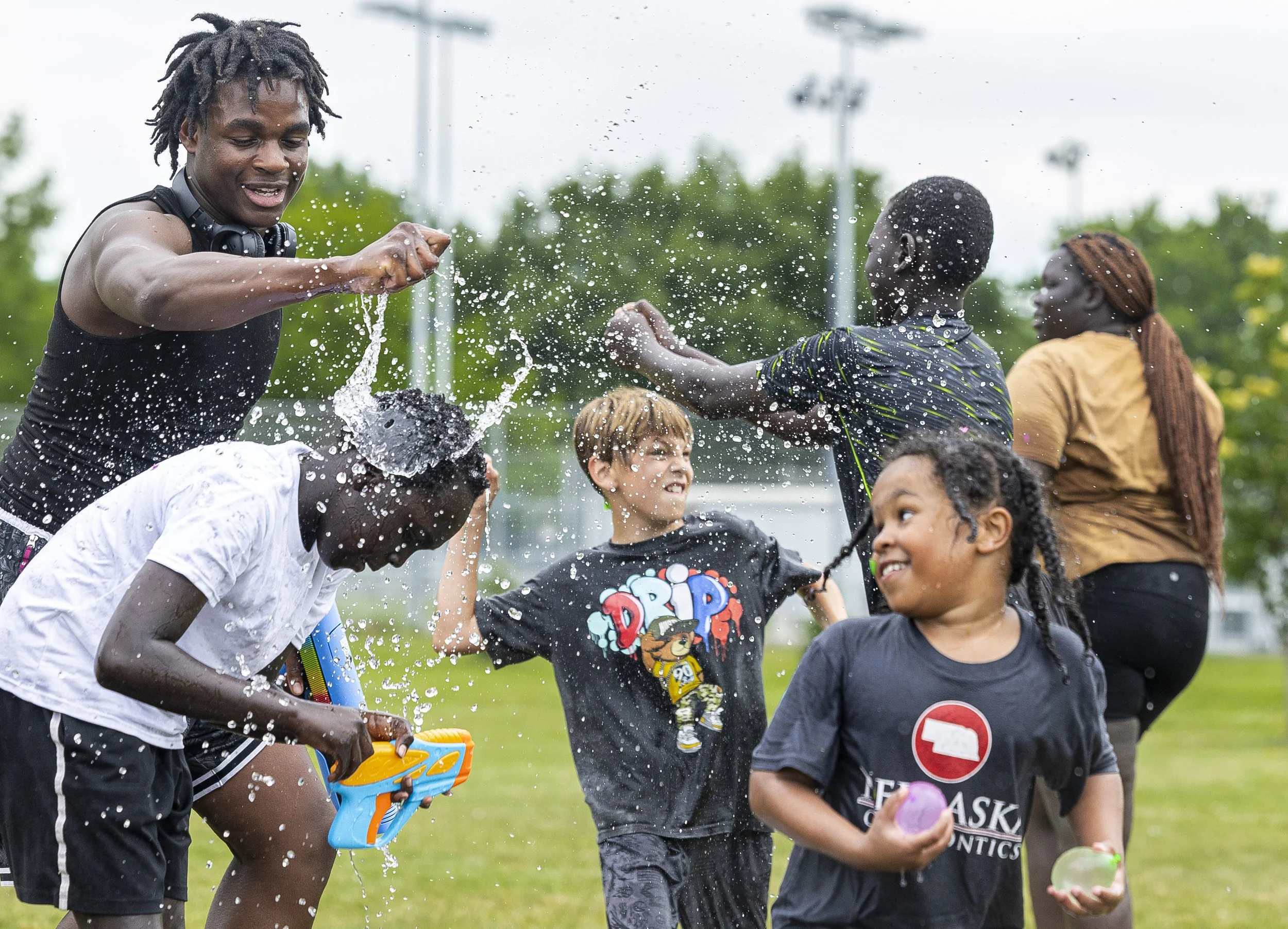  Elijah Harris (from left) breaks a water balloon over the head of Joshua Williams, 12, as Alicio Brown, 9, throws a water balloon, and Amarien Bonebright, 8 escapes carrying ammunition during a Community Day event put on by Black African Family at W