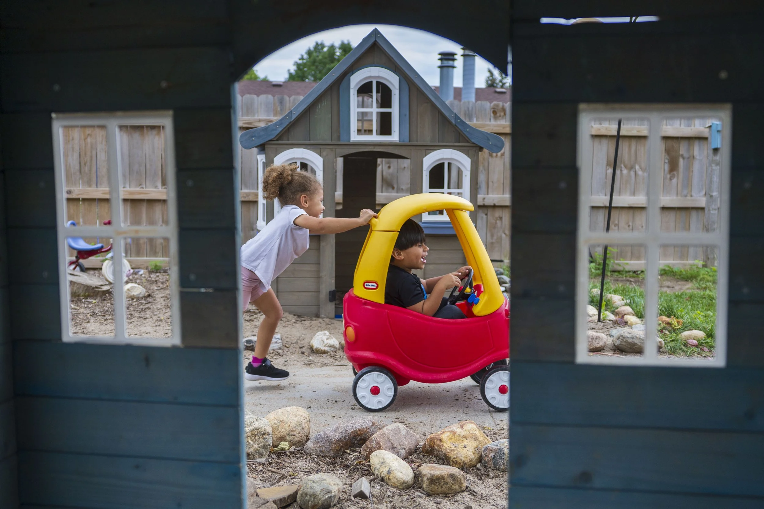  Framed through a children’s play set, Jordyn Anderson, 3 (from left), pushes her friend Jordan Lara, 4 in a Cozy Coupe toy while at the playground outside at Las Abejitas located inside of First Lutheran Church on Friday, Aug. 23, 2024, in Lincoln. 