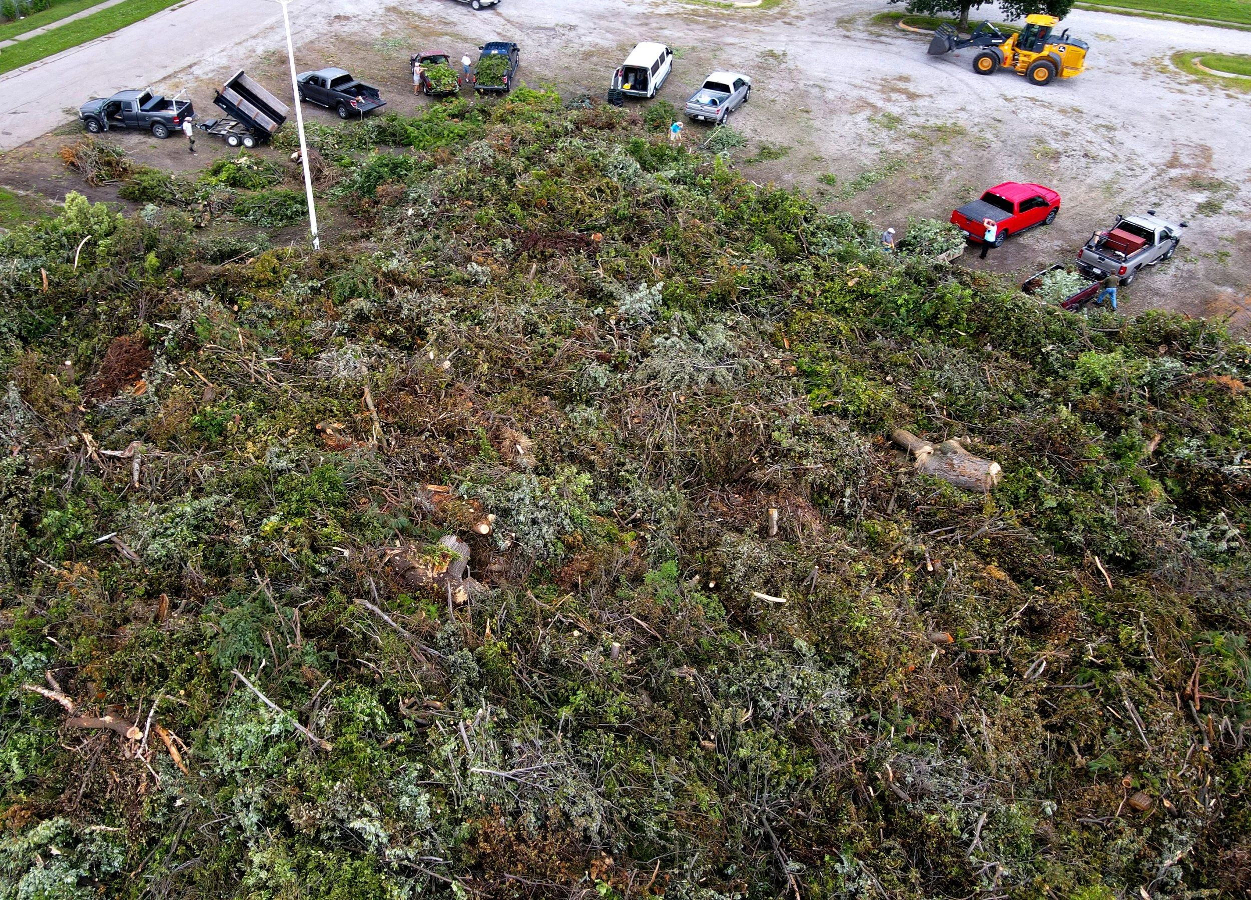  Cars and trucks circle around a growing pile of storm derbies as they drop off tree limbs and refuse at a storm debris drop off site in the Star City Shores parking lot on Monday, Aug. 11, 2025, in Lincoln 