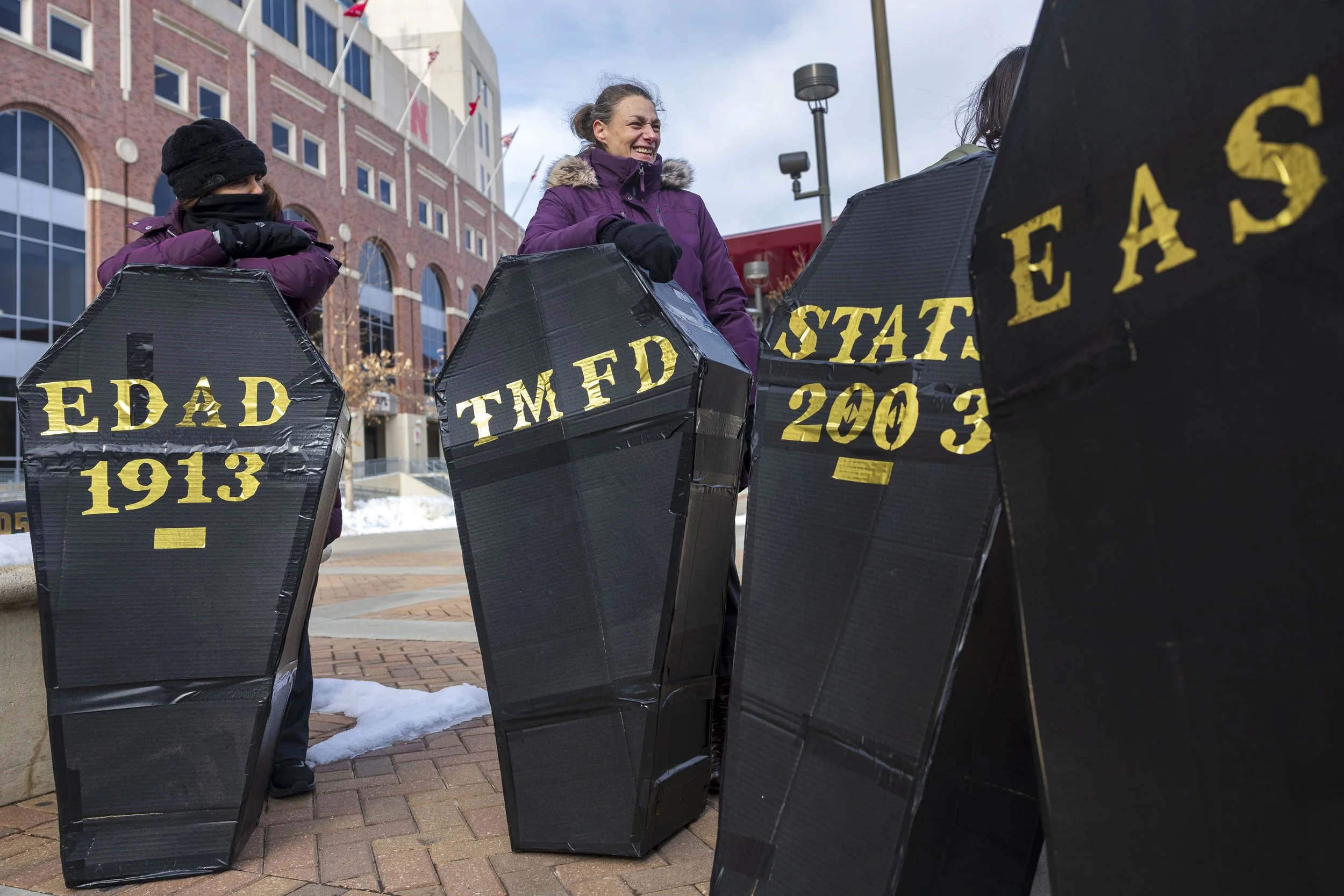  Teaching, Learning &amp; Teacher Education Professor Theresa Catalano, from left, and Department of Educational Administration professor Sarah Zuckerman hold cardboard coffins as they wait to join a New Orleans–style funeral procession led across ca