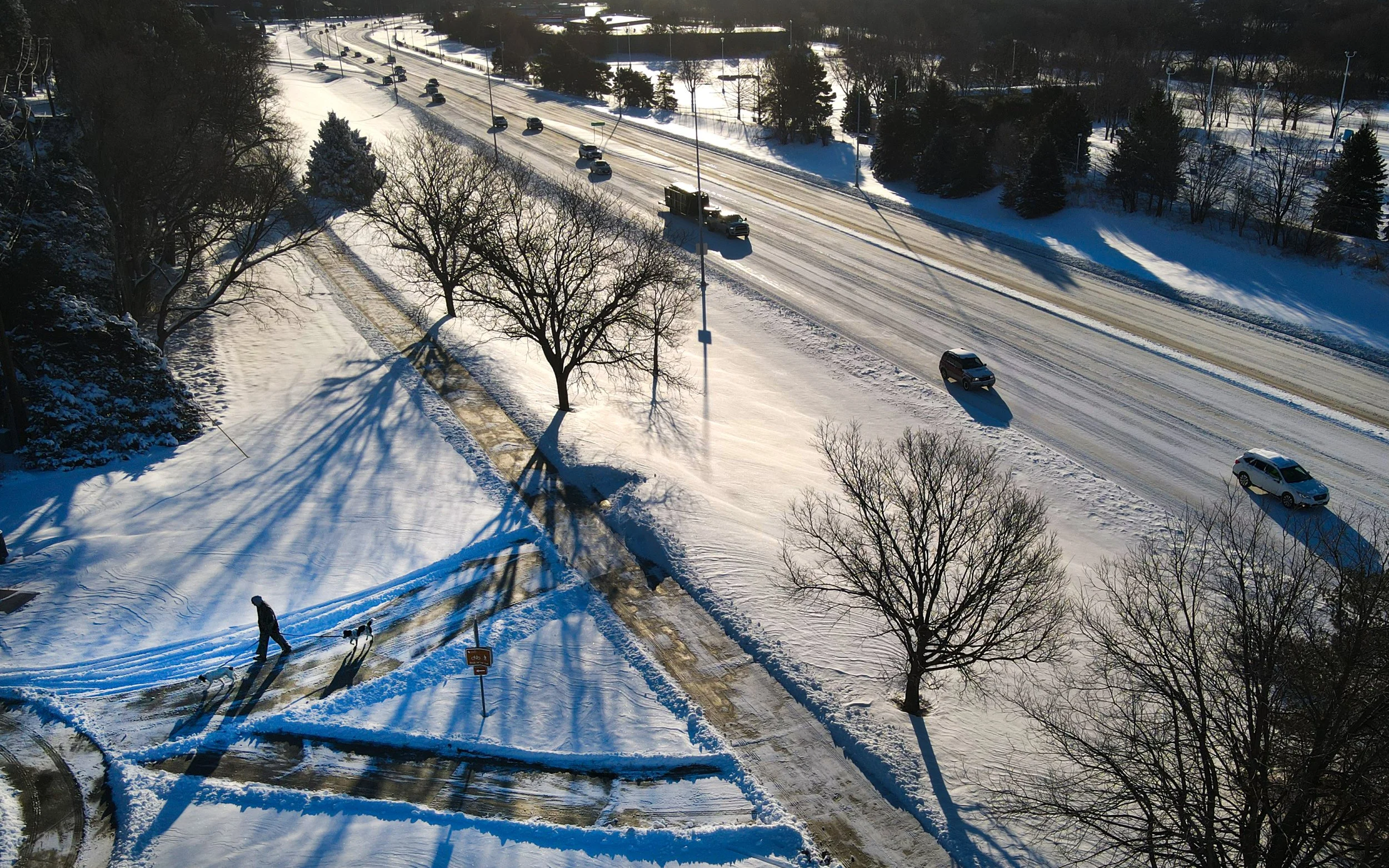  A man walks his two dogs along the Rock Island Trail as traffic navigates snow covered roads on Nebraska Parkway on Friday, Feb. 20, 2026, in Lincoln.  A winter storm that blanketed Lincoln in snow Thursday firmly squashed any thoughts that February