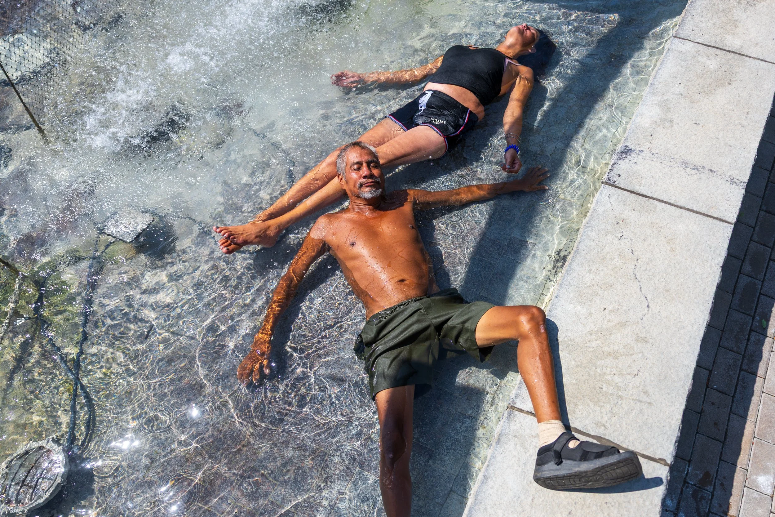 Michael and Tina White cool off in the Ken Good Fountain in Union Plaza on Monday, July 27, 2026, in Lincoln. Michael, who is wearing a boot, keeps it out of the water while Tina supports him.
