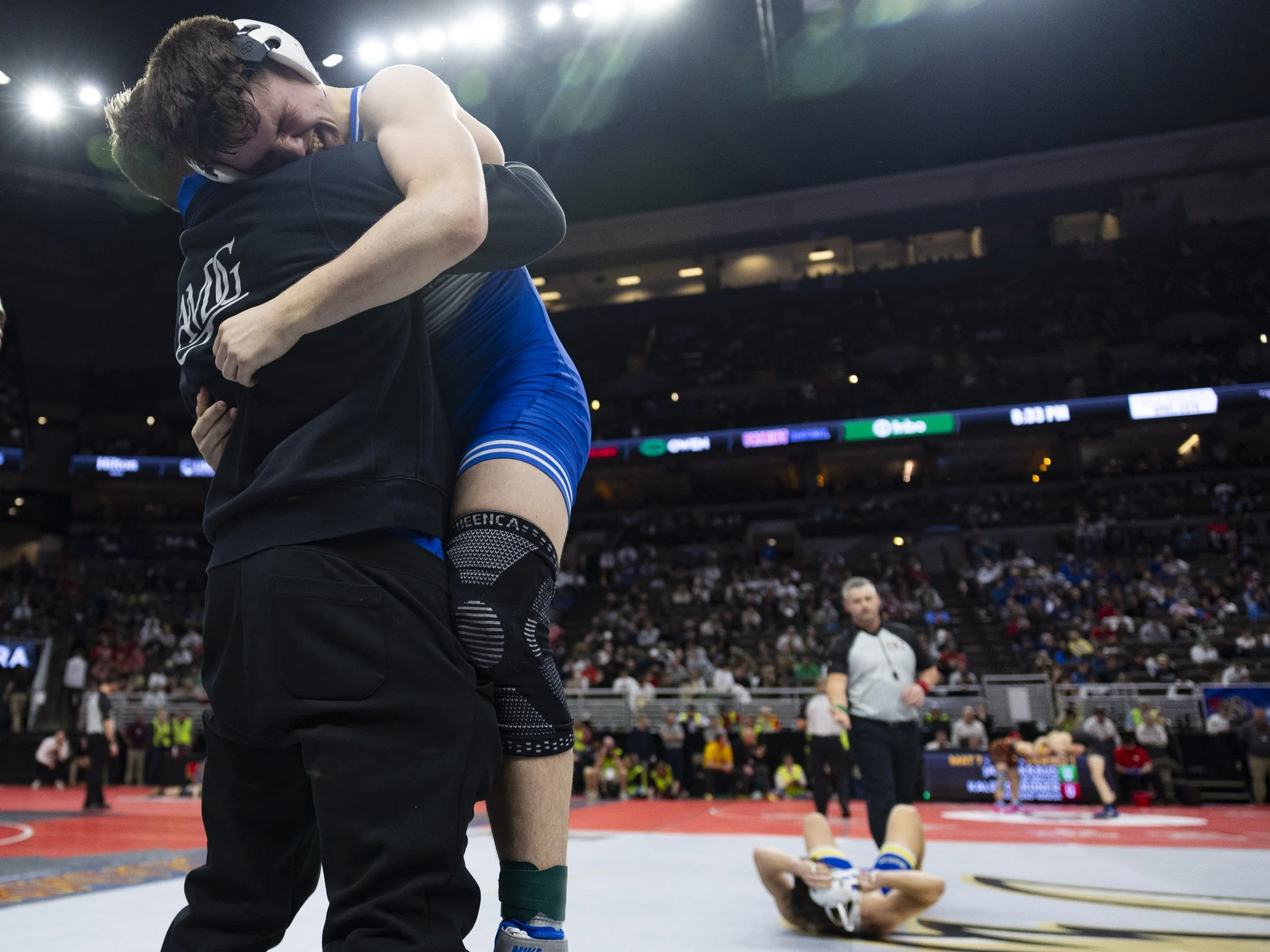 Creighton Prep's Kaleb Griffith leaps into the arms of his coach Rowan Stander after defeating Kearney's Braxton Robinson in a Nebraska boys high school wrestling state tournament Class A 157 pound seminal round match at the CHI Health Center in Omah
