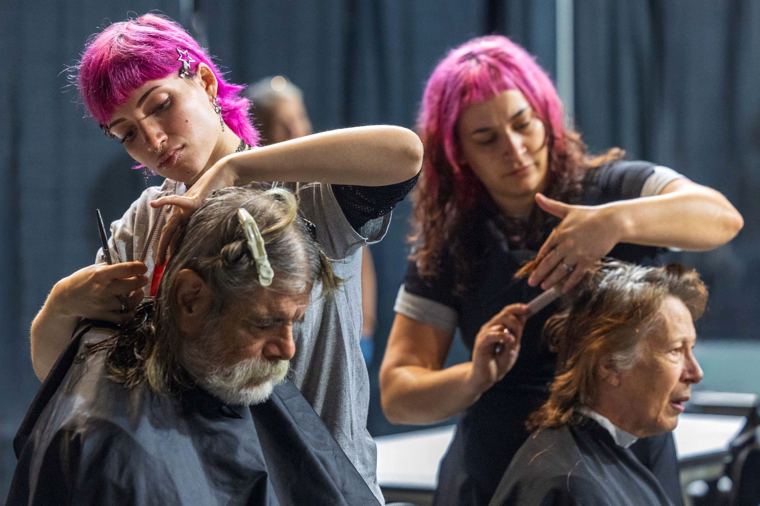 Entourage Institute of Beauty cosmetologists Cris Santiago, top left, and Aly Bangert, top right, cut hair for Adam Lucero, bottom left, and Kimberlee Turvey during the Project Connect event on Wednesday, Sept. 30, 2026, at Pinnacle Bank Arena.