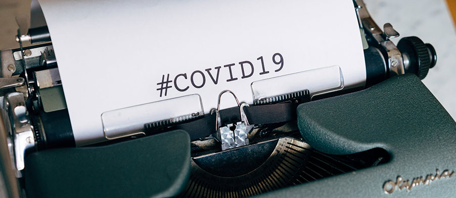 Typewriter with white paper that reads “#COVID19”
