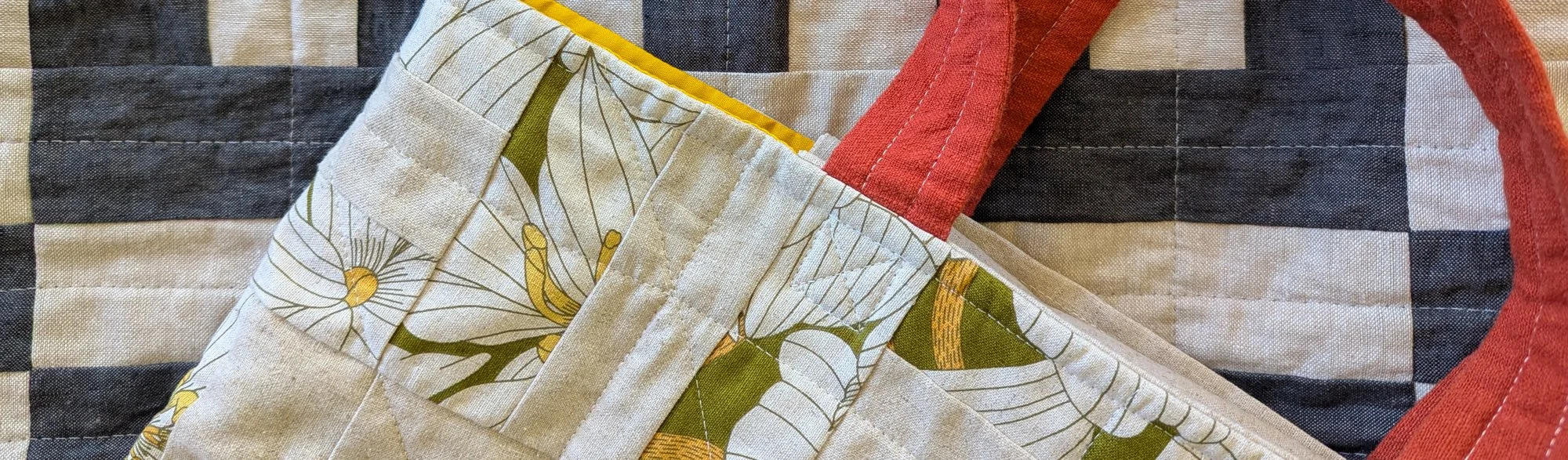 Close-up of a colorful geometric quilt with various rectangles and triangles in shades of yellow, red, pink, blue, and green.