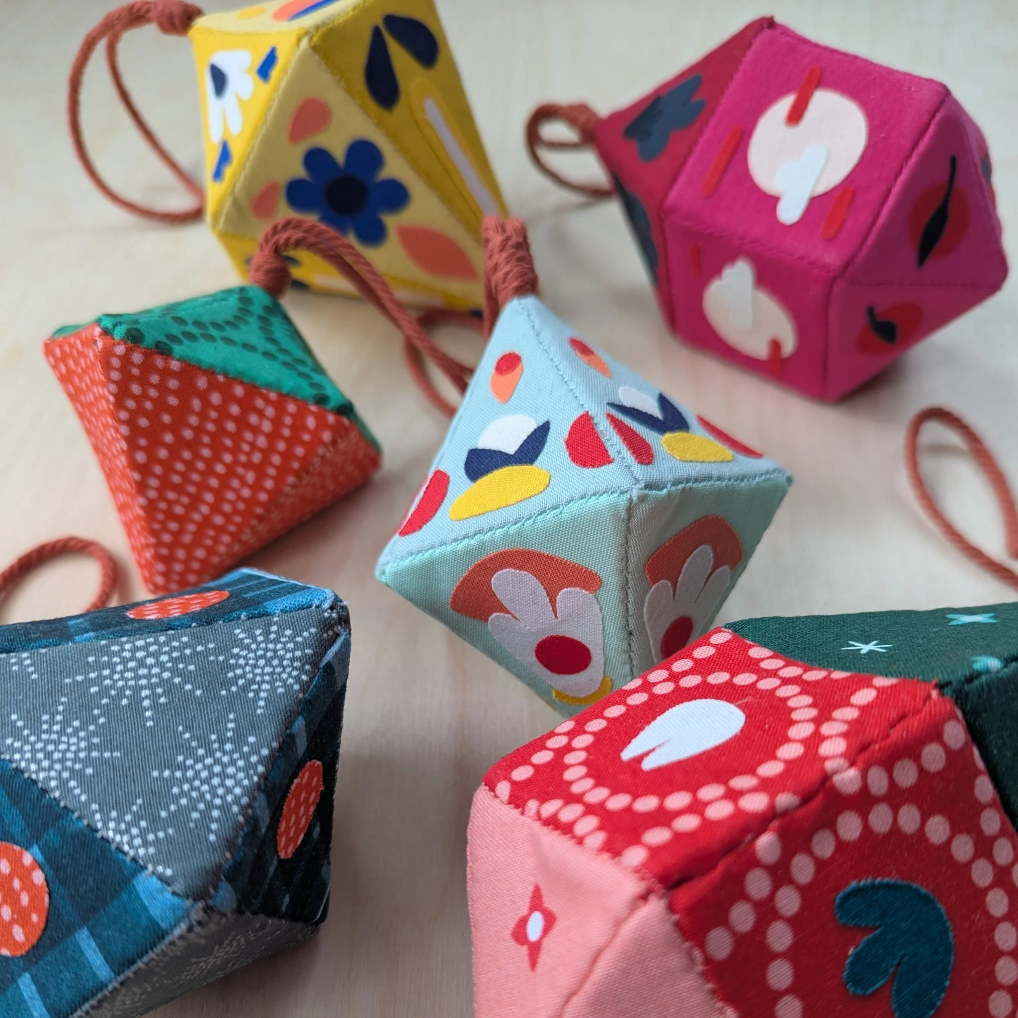 Colorful fabric ornaments with various patterns and colors on a light surface.