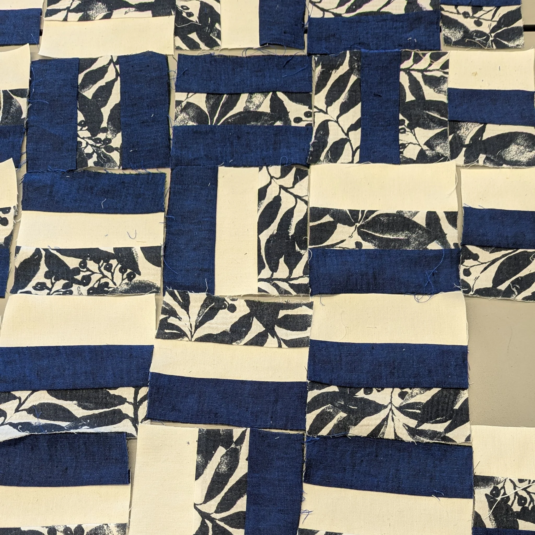 Close-up of a woven fabric with strips of blue, cream, and patterned black-and-white fabric creating a checkered pattern.