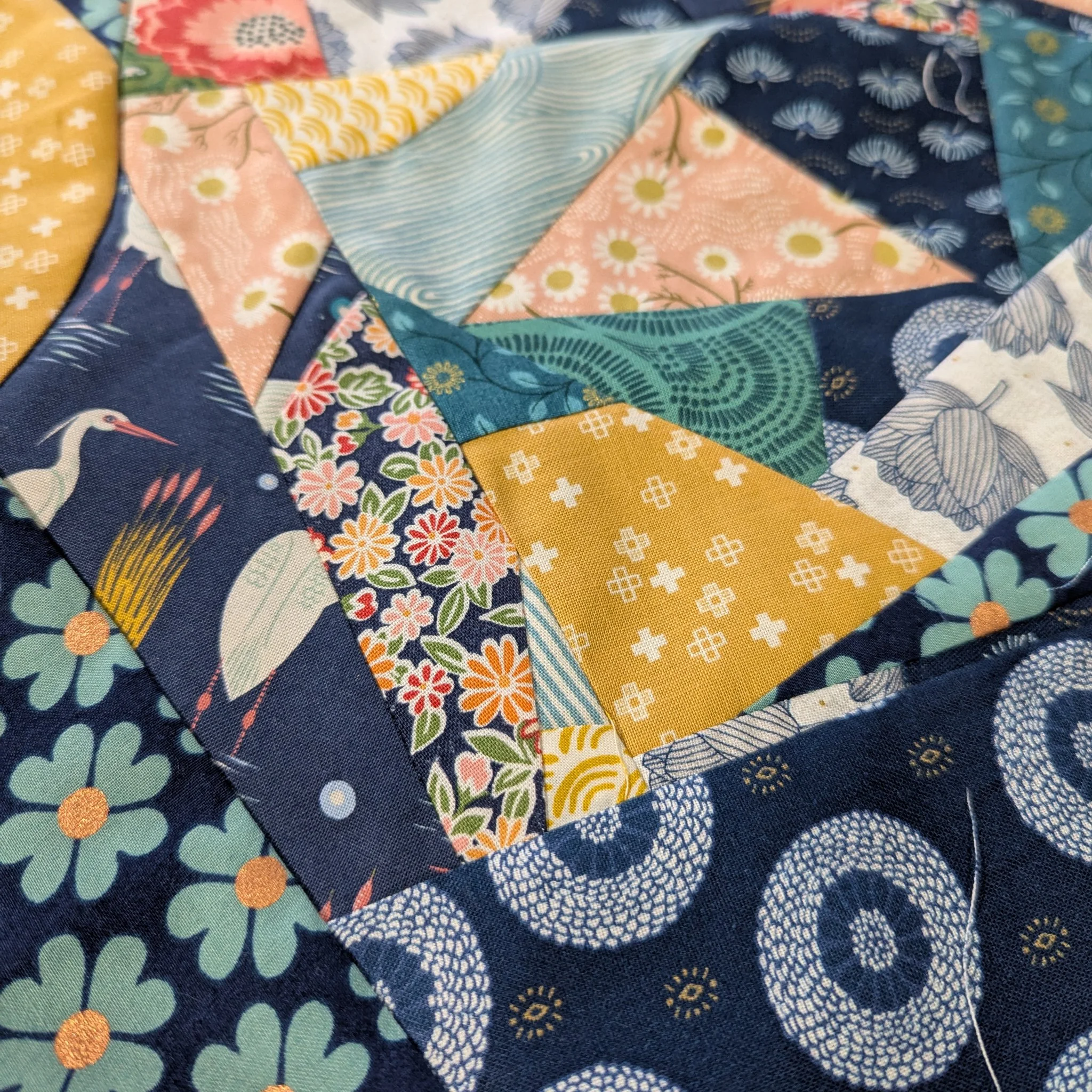 Close-up of a quilt made from colorful fabric patches with floral, geometric, and animal patterns.