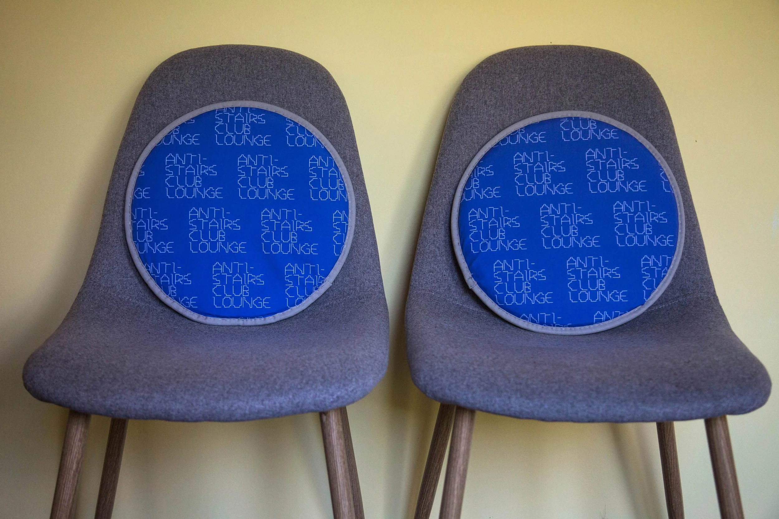 Twin chairs with custom Anti-Stairs-Club-Lounge-patterned cushions.