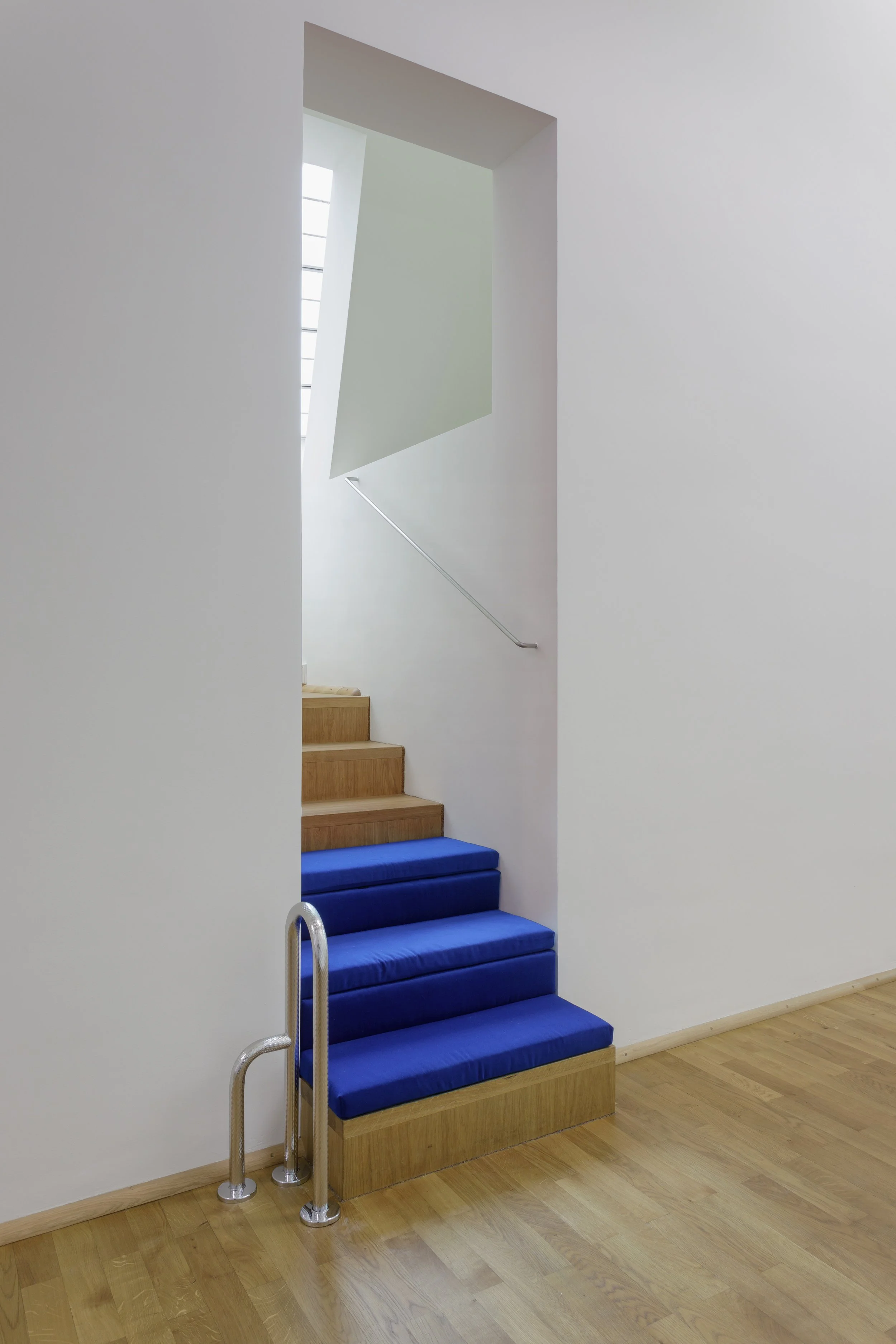 A narrow 6-step stairway to a small balcony. The bottom three steps are covered by velour cushions, sized to fit and cover the steps. To the side is a grab bar that makes it a little easier for me (and maybe others) to get up and down from sitting.