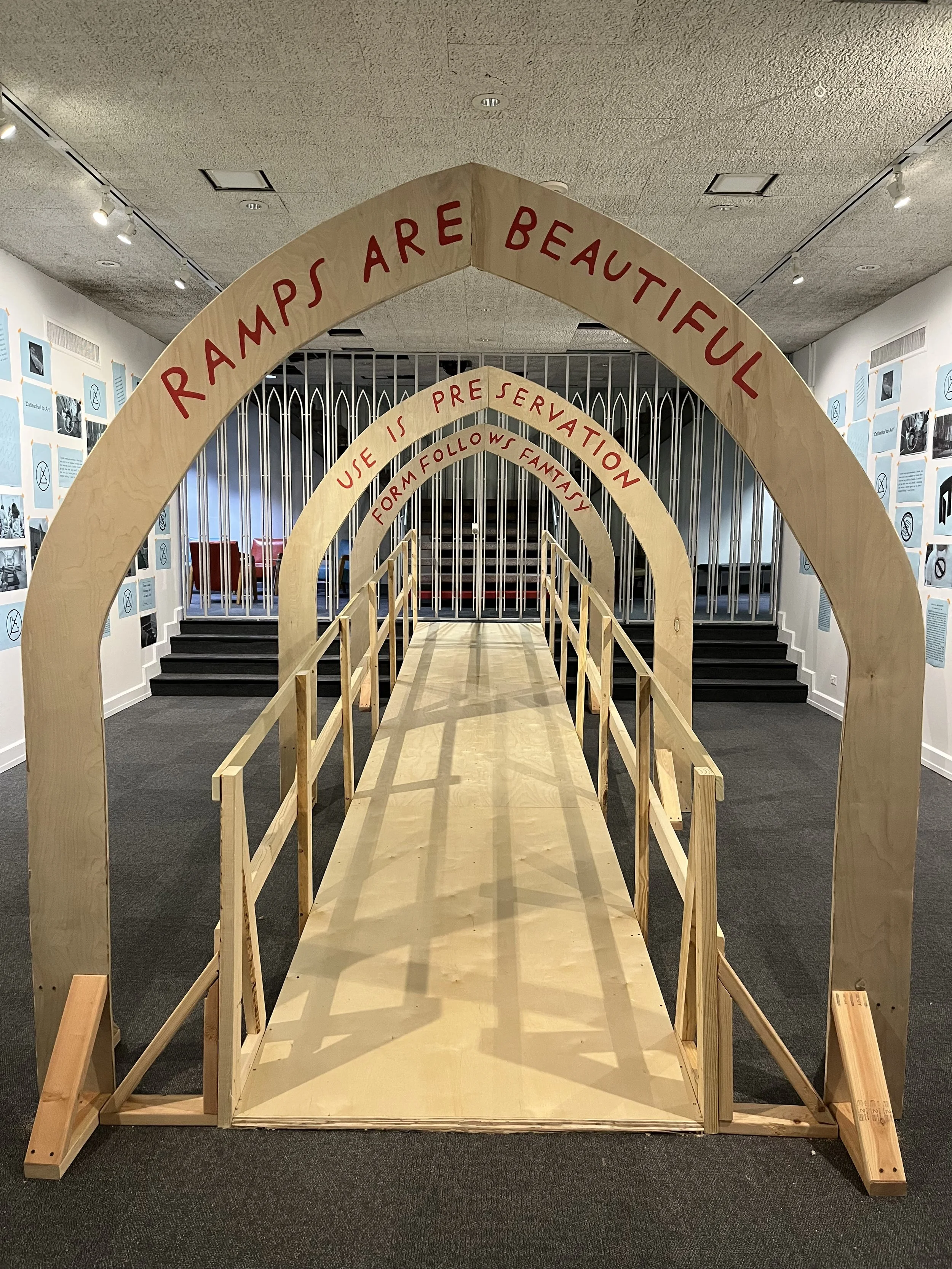 A plywood ramp with three arches. Each arch has a phrase in my handwriting. In the foreground “Ramps are beautiful,” then “Use is preservation,” and then “Form follows fantasy.” The shape of the arches is gothic (comes to a soft point at the peak).