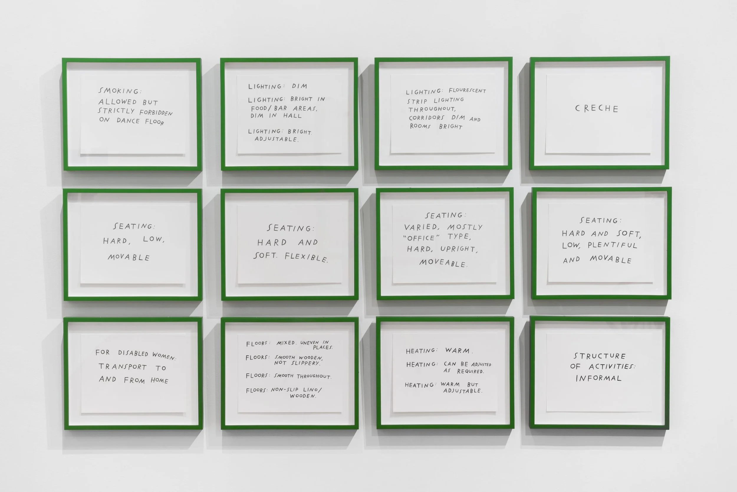 A grid of twelve framed drawings with green borders frames on a white gallery wall. Each contains handwritten text with notes on accessibility, such as “smoking allowed but strictly forbidden on the dance floor” and “seating: Hard and soft. Flexible”