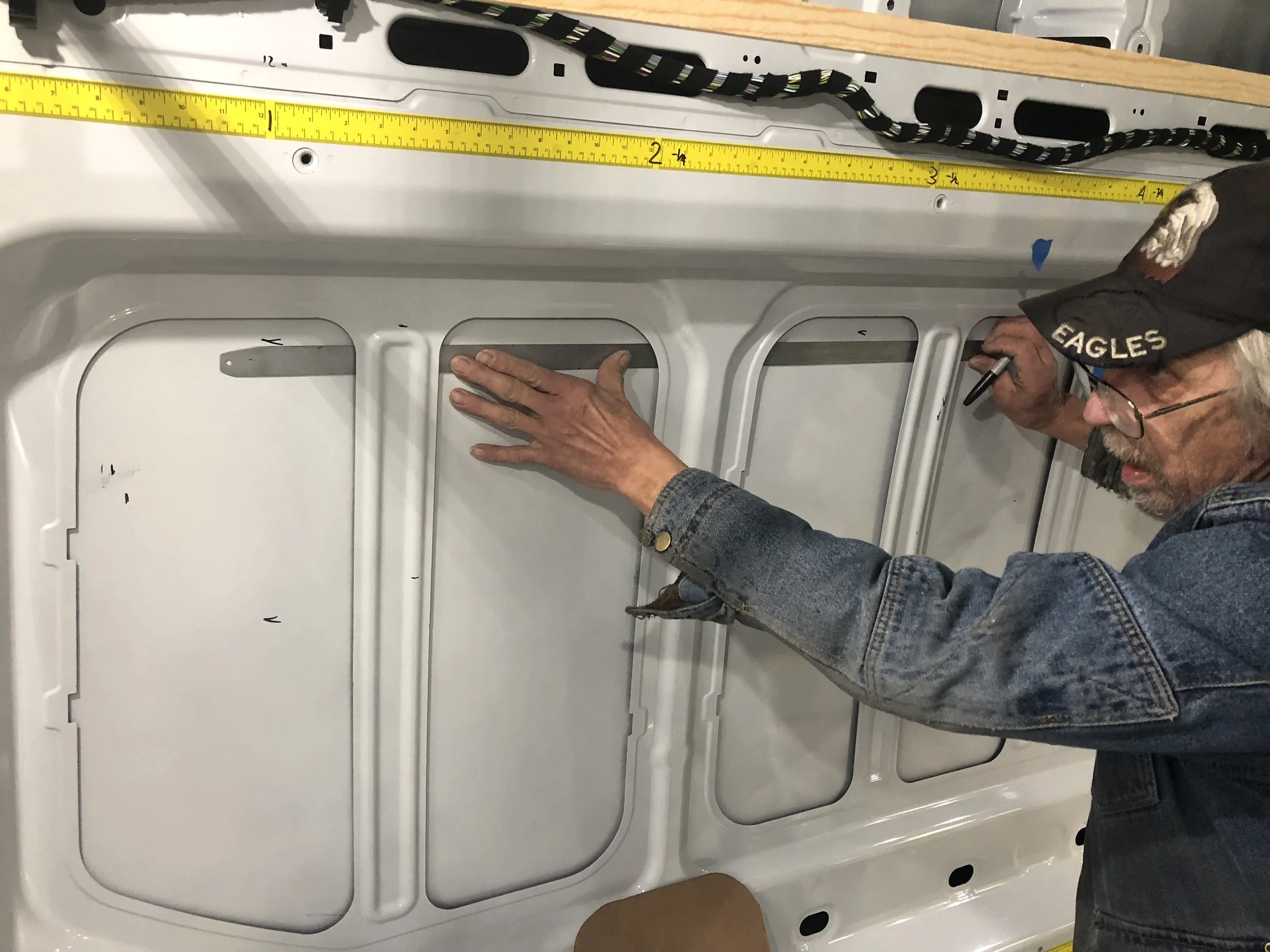This is the window behind the driver’s side. It’s placed as far forward as possible. The top, left, right, and bottom edges have been measured and marked. Now George is connecting the lines.