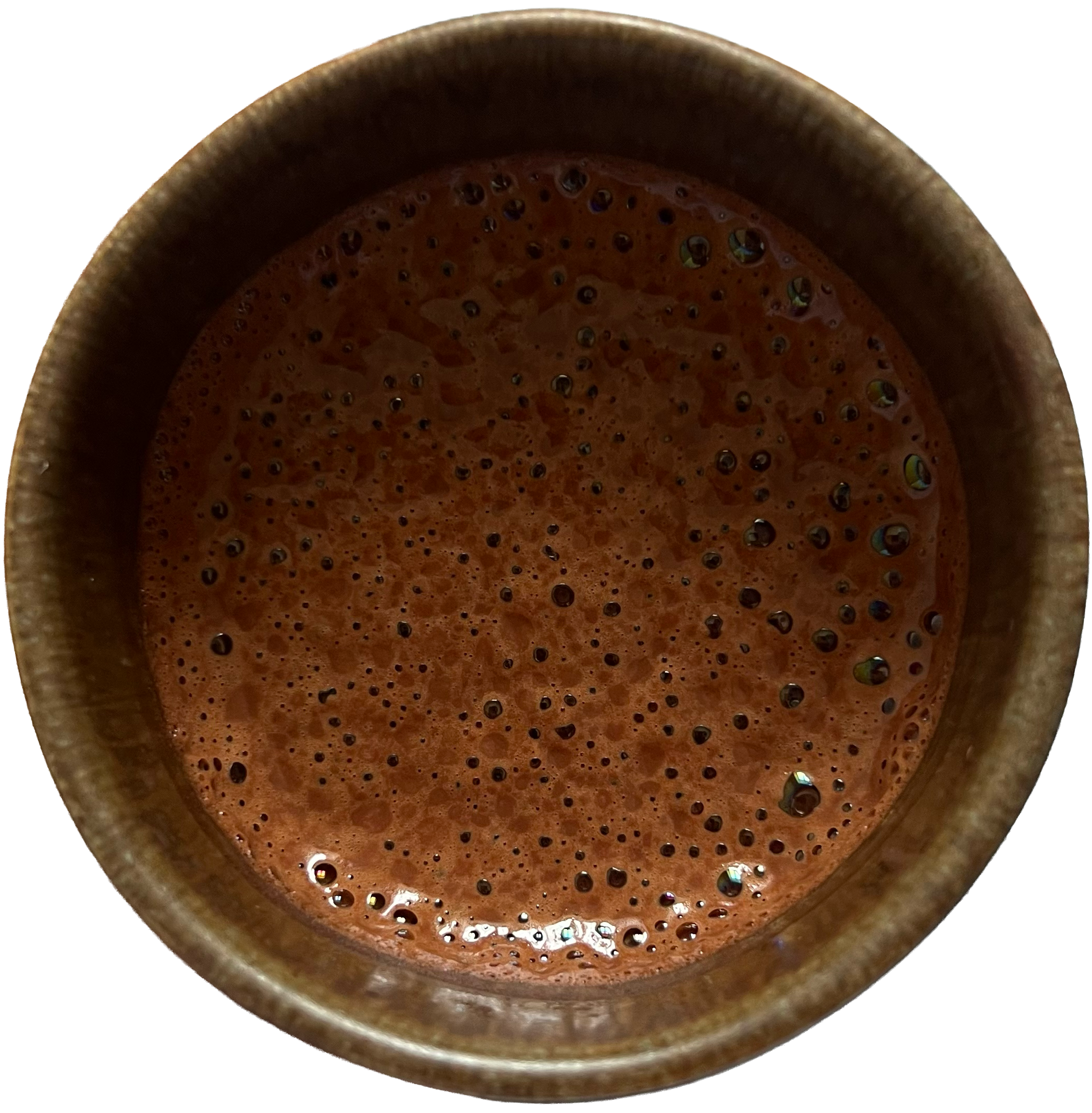 Close-up of a metallic cup filled with hot, frothy coffee with bubbles on the surface.