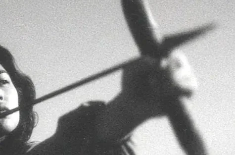 Black and white photograph of a woman holding a sword and a large sword-shaped object.