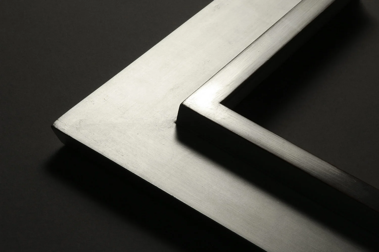 Raking light image of white gilded frame with smooth surface and no visible seam.