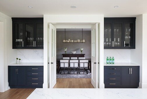 You can never go wrong with a charcoal and crisp white color palette. White Shaker cabinetry with step detail and stainless toe kicks are beautifully offset with the contrasting kitchen island and buffet areas of this Water Mill kitchen renovation.⁠⠀