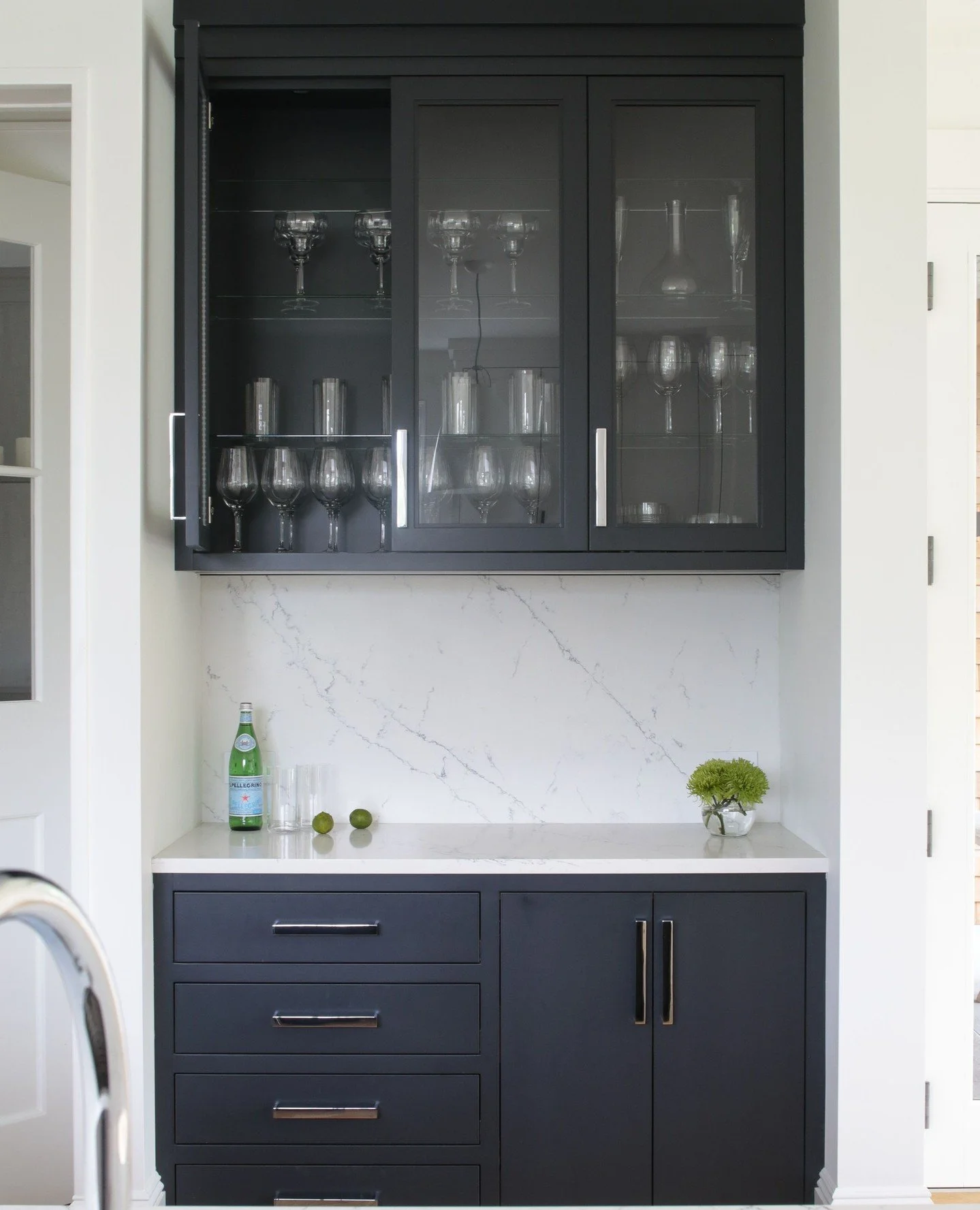✨ Chic meets functional. This built-in bar pairs matte black cabinetry, sleek hardware, and glass-front uppers with a clean quartz backsplash&mdash;proving that even the smallest spaces can make a big statement. 🍸✨