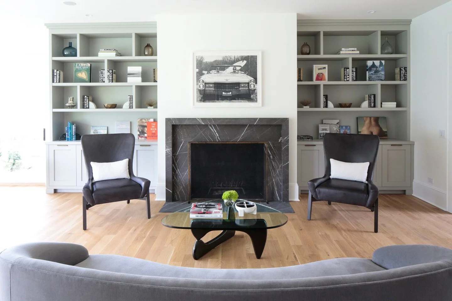 Captivating contrast 🖤 Symmetry is the secret ingredient for sophisticated balance. ⚖️ In this design, the matching built-ins and chairs frame the stunning dark marble fireplace, creating a sense of order and calm. It's the perfect formula for a cla