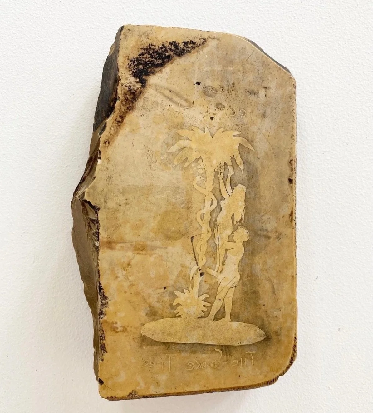 A late 19th or early 20th century lithography stone with an erotic scene of Eve using Adam&rsquo;s p*nis to reach apples (coconuts). It was an ad for a cigarette lighter.
At the top is says &ldquo;the new cigarette lighter&rdquo; and at the bottom &l