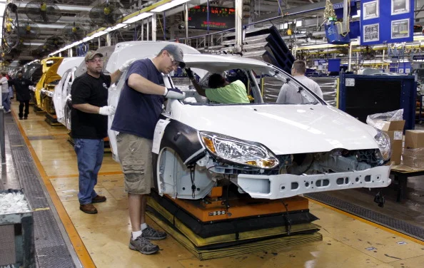 Workers build a Ford Focus on the assembly line at the Ford Motor Co.'s Michigan Assembly Plant December 14, 2011 in Wayne, Michigan. (Photo by Bill Pugliano/Getty Images)