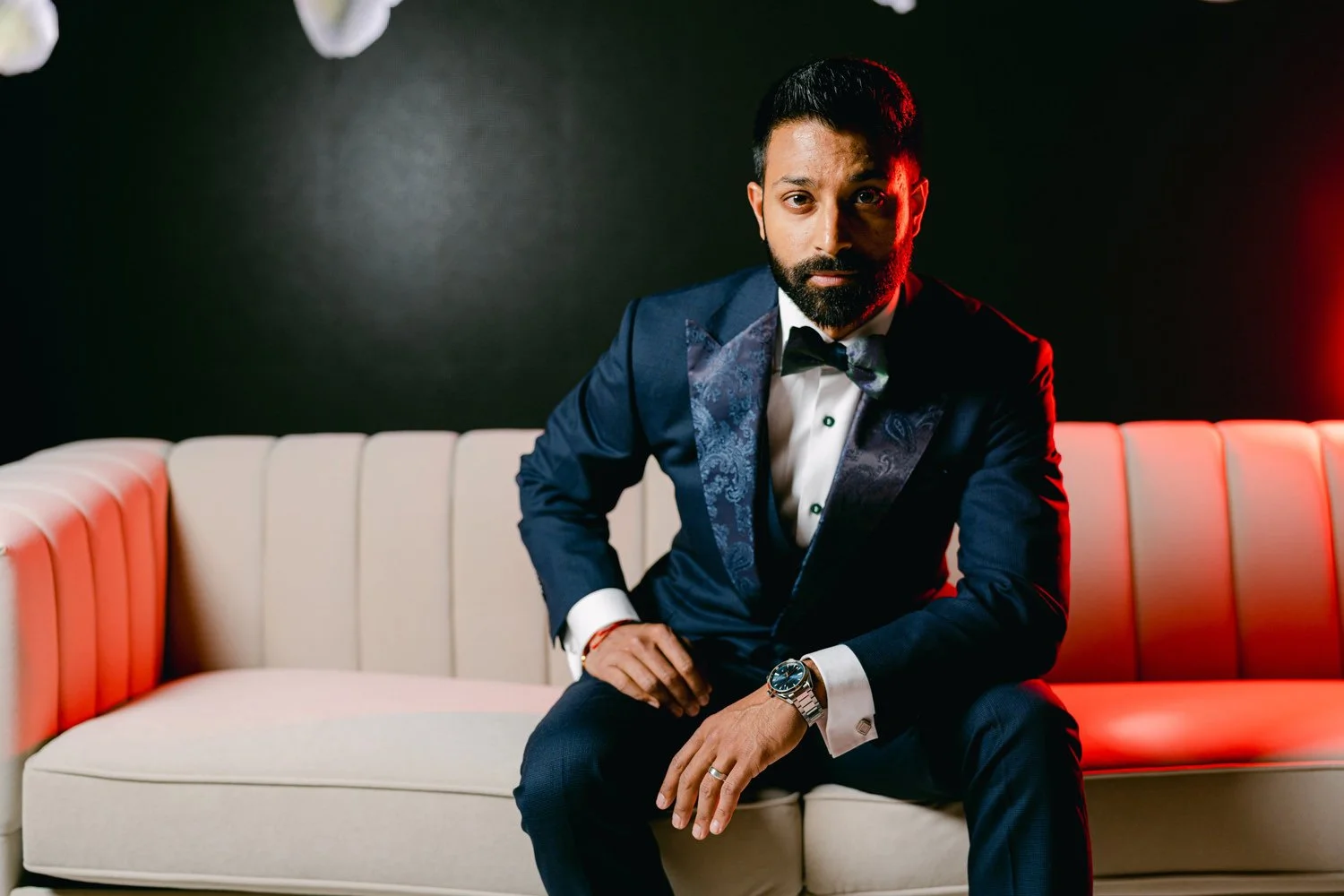 Indian groom wearing a navy tux looking directly at the camera