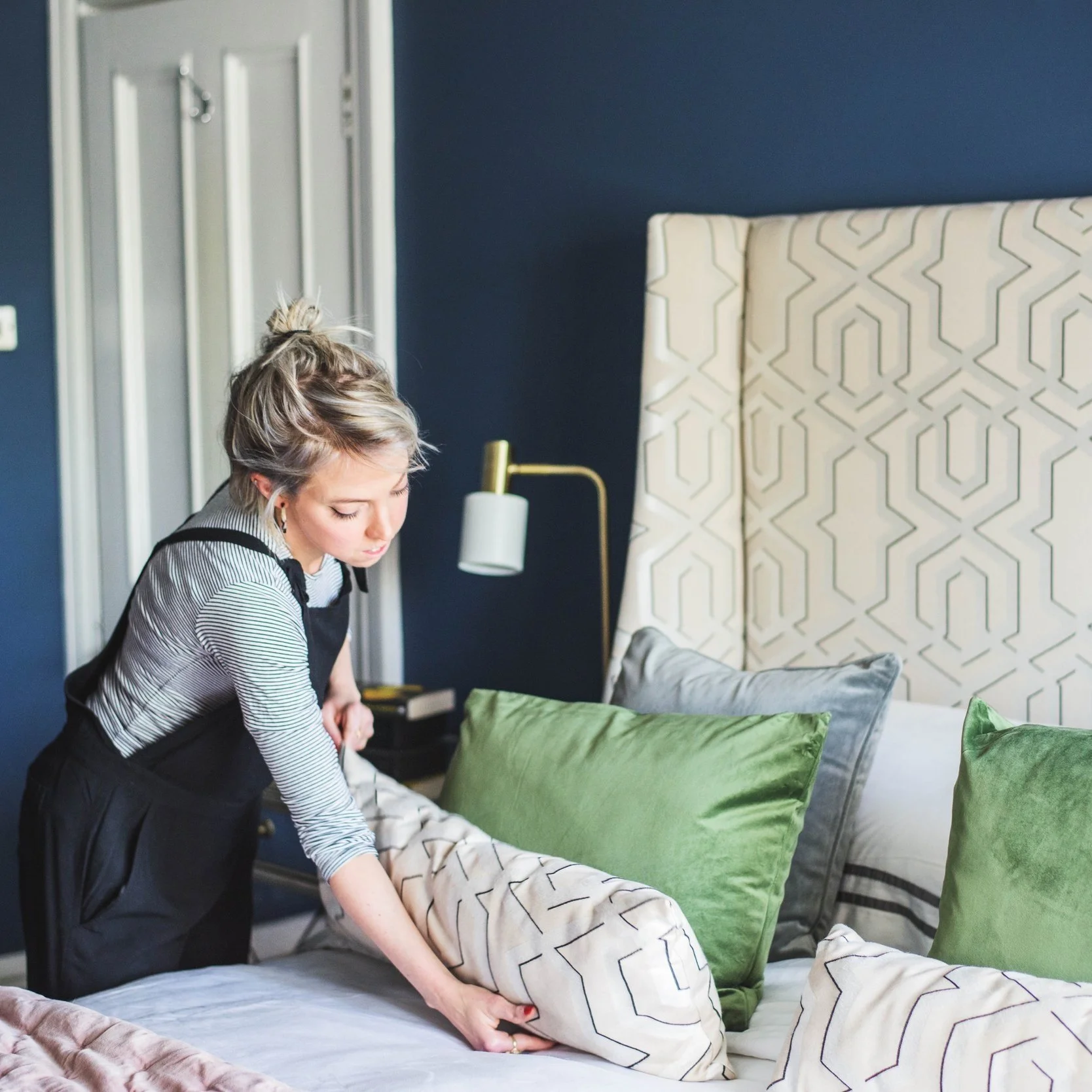 Interior Designer Ruth from Litterarty placing green velvet cushions on bed while staging a bedroom she interior designed. Showing colour pops, adding texture and styles.
