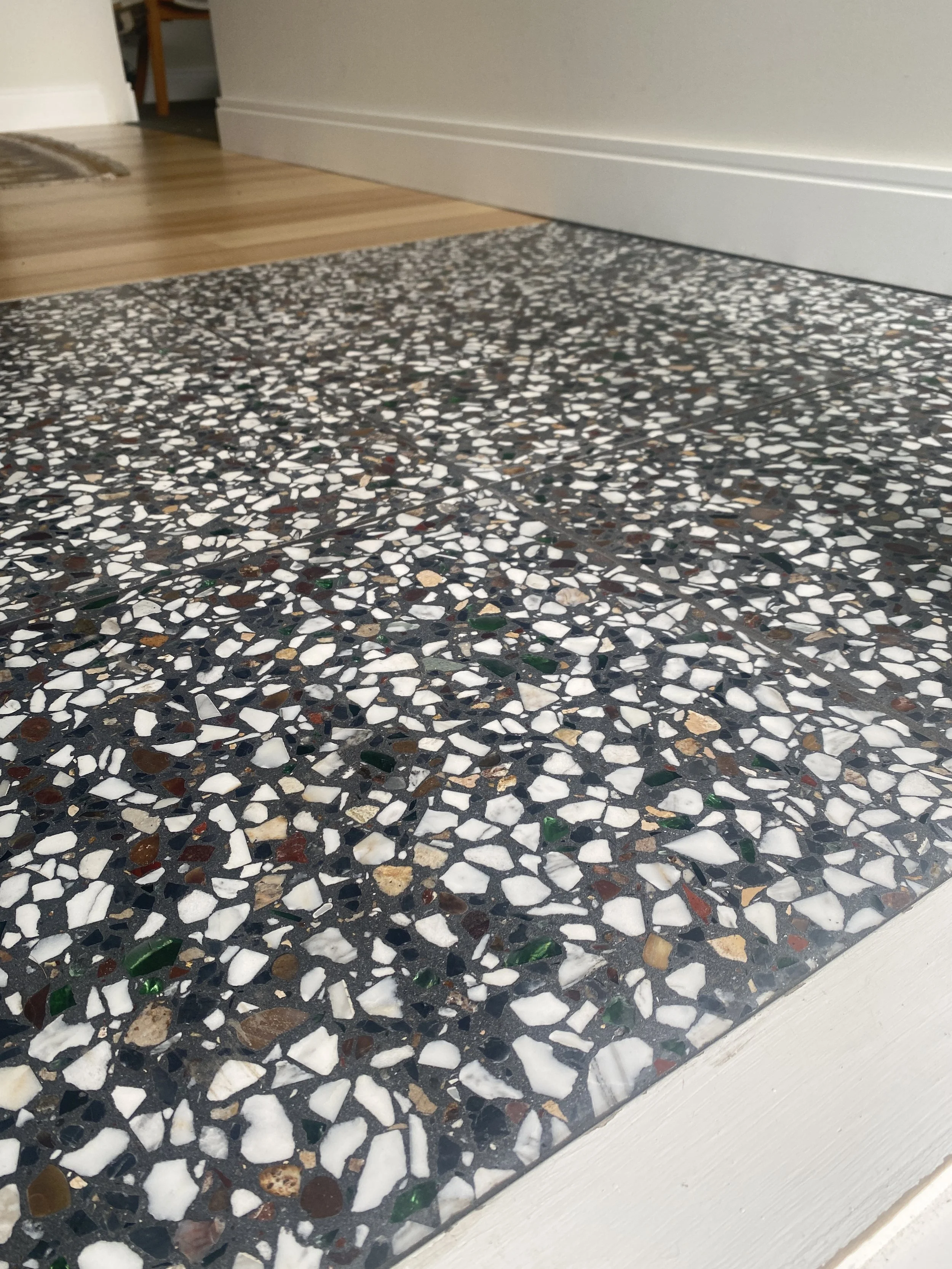Close-up of a terrazzo floor with black, white, brown, and green speckles.