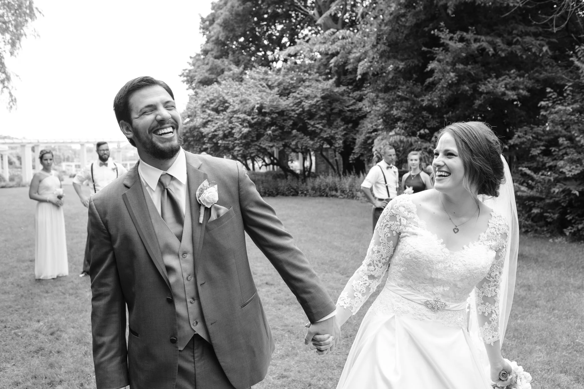 Black and white of bride and groom holding hands while laughing and walking at Sinnissippi Gardens in Rockford Illinois.