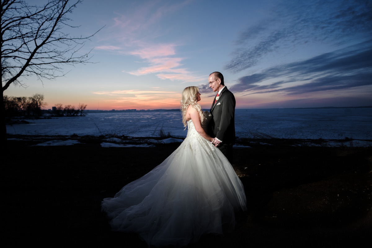 Bride and groom kissing as sunsets behind them with frozen lake in downtown Madison, Wisconsin.