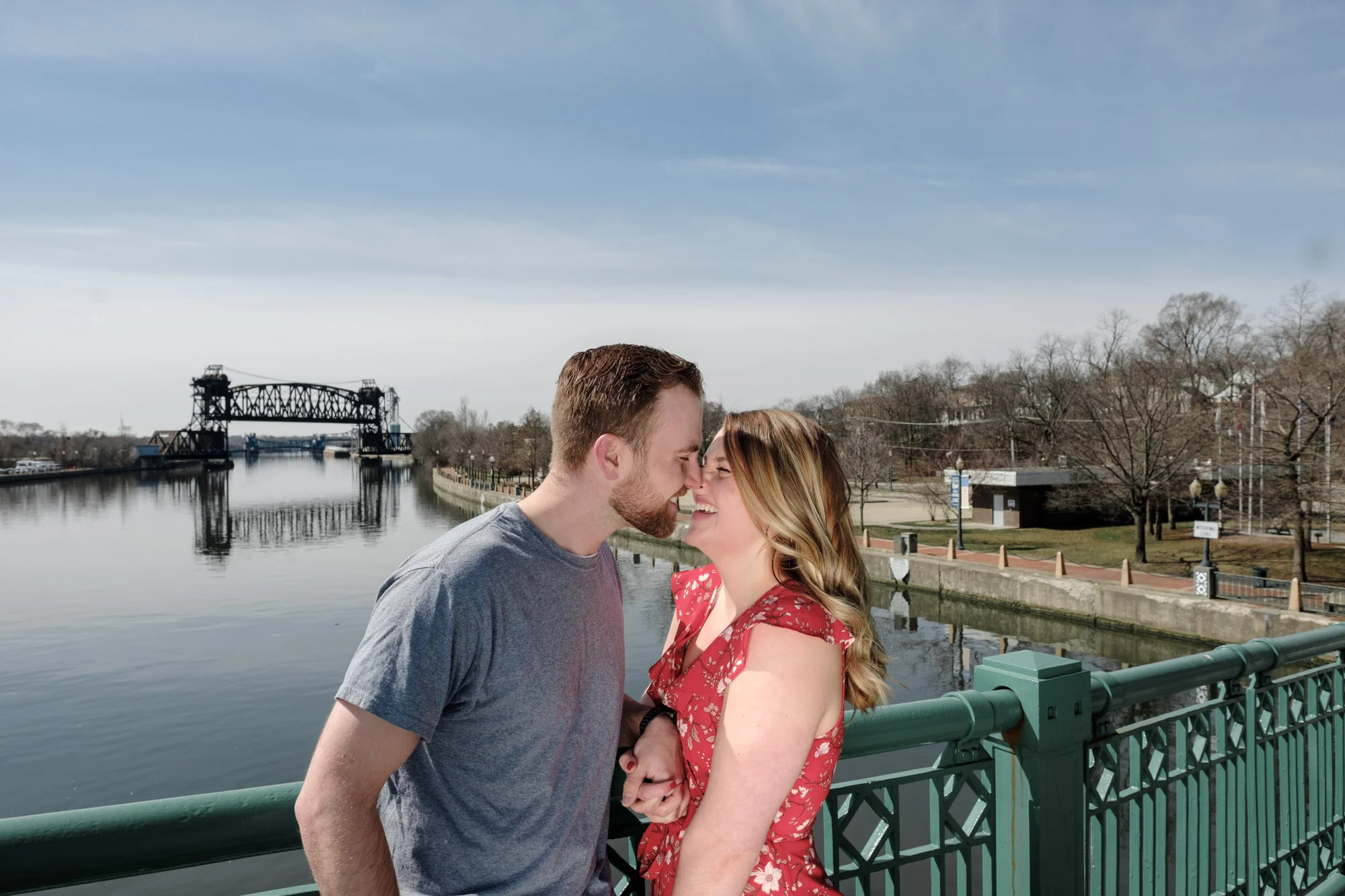 Couple kissing on bridge with beautiful blue sky above the river in Joliet, Illinois