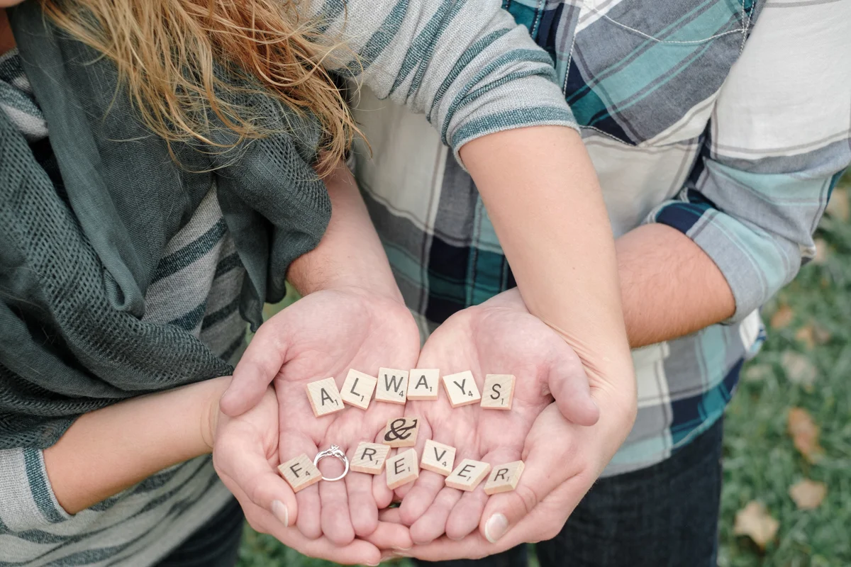 couple holding engagement ring and scrabble letters