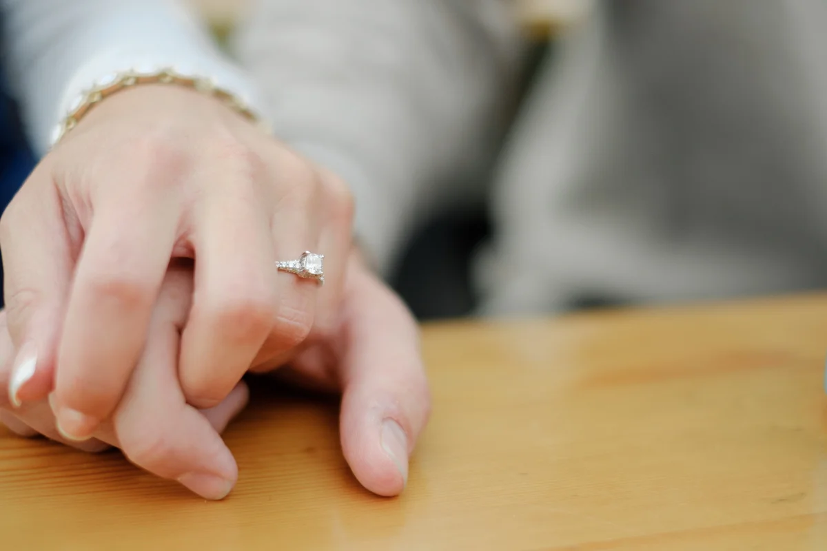 Couple holding hands with engagement ring proudly displayed on the roof top of Taco Betty’s in downtown Rockford