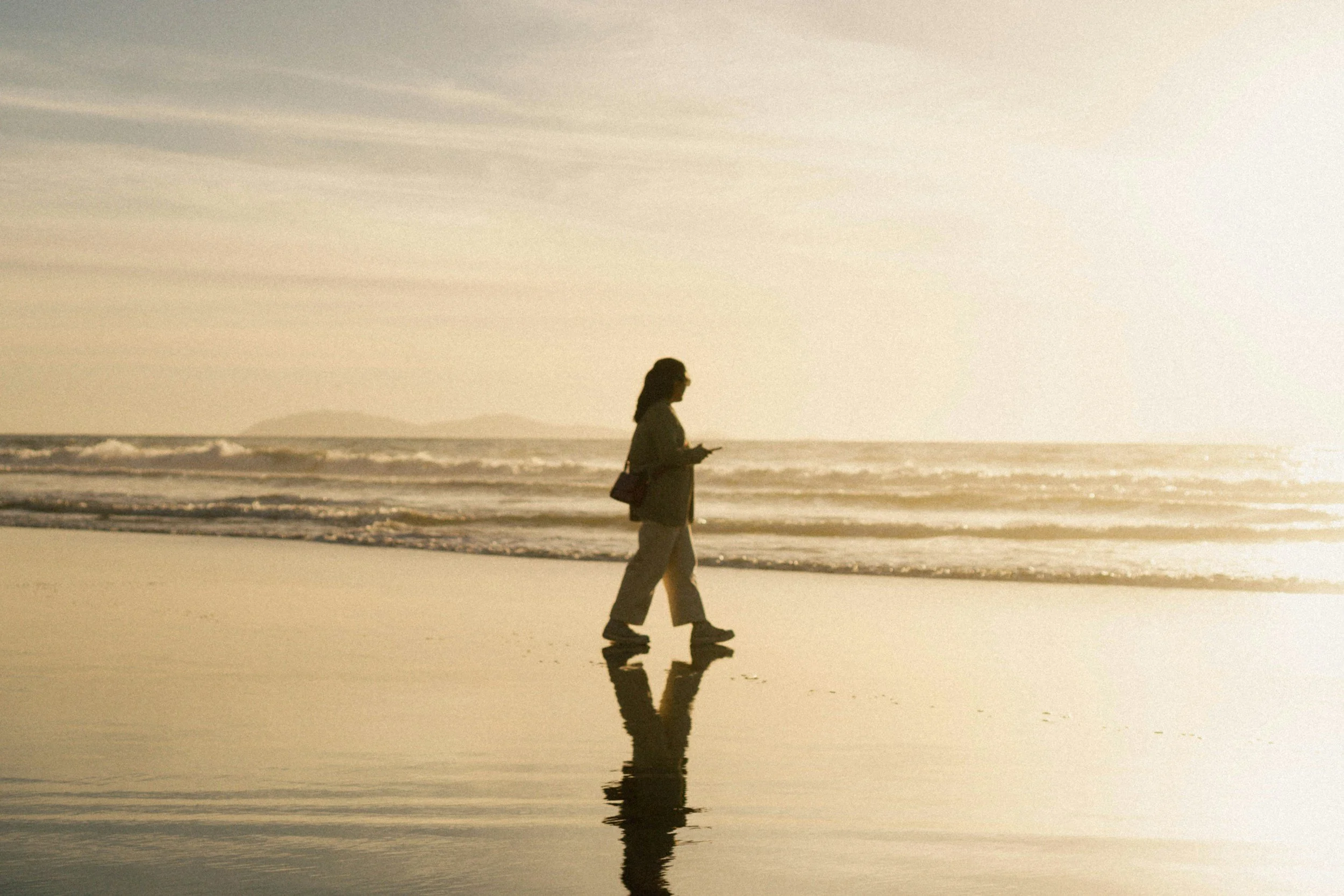 muted photo of woman walking on the beach