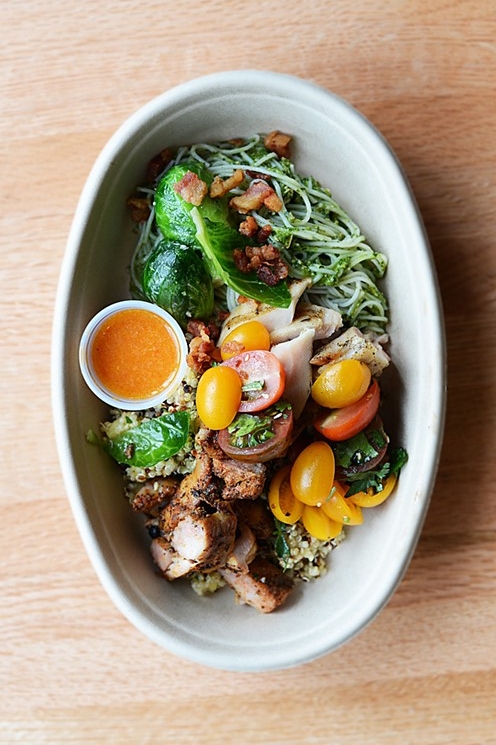 White bowl  filled with variety of steam vegetables and grilled chicken sitting on table top