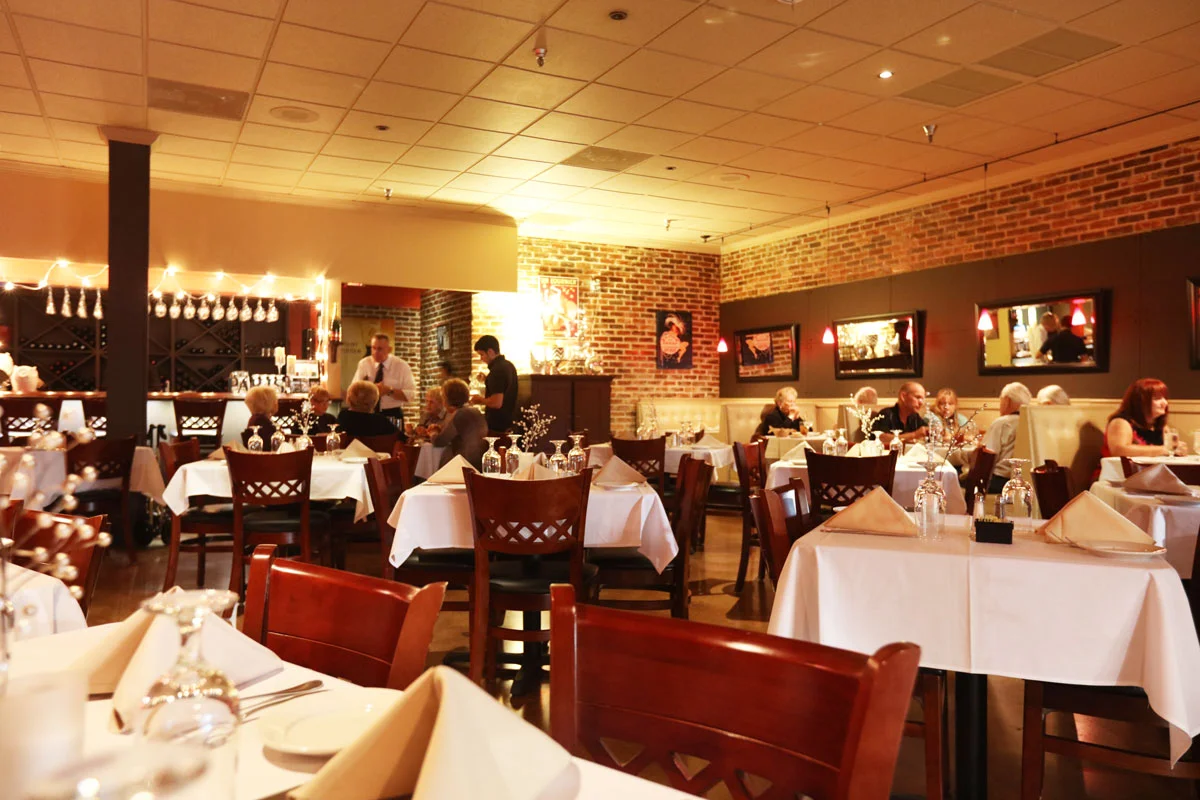 restaurant dining room with preset tables, with people sitting at the table interacting 