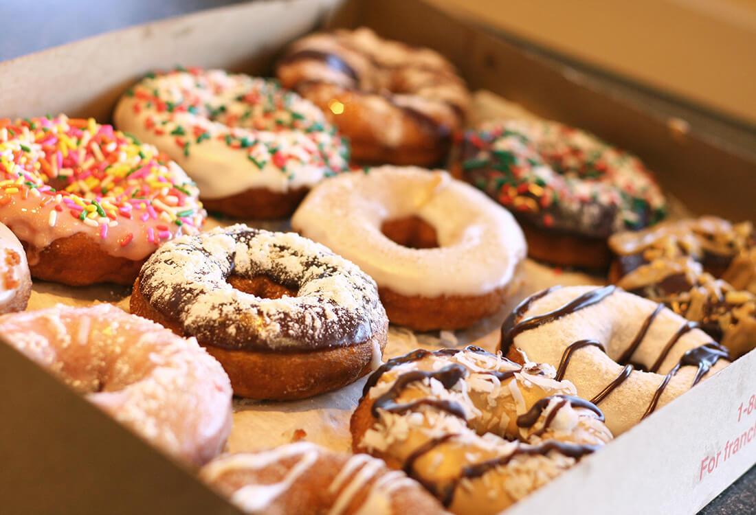 Assorted glazed donuts in a box with various topping and glaze