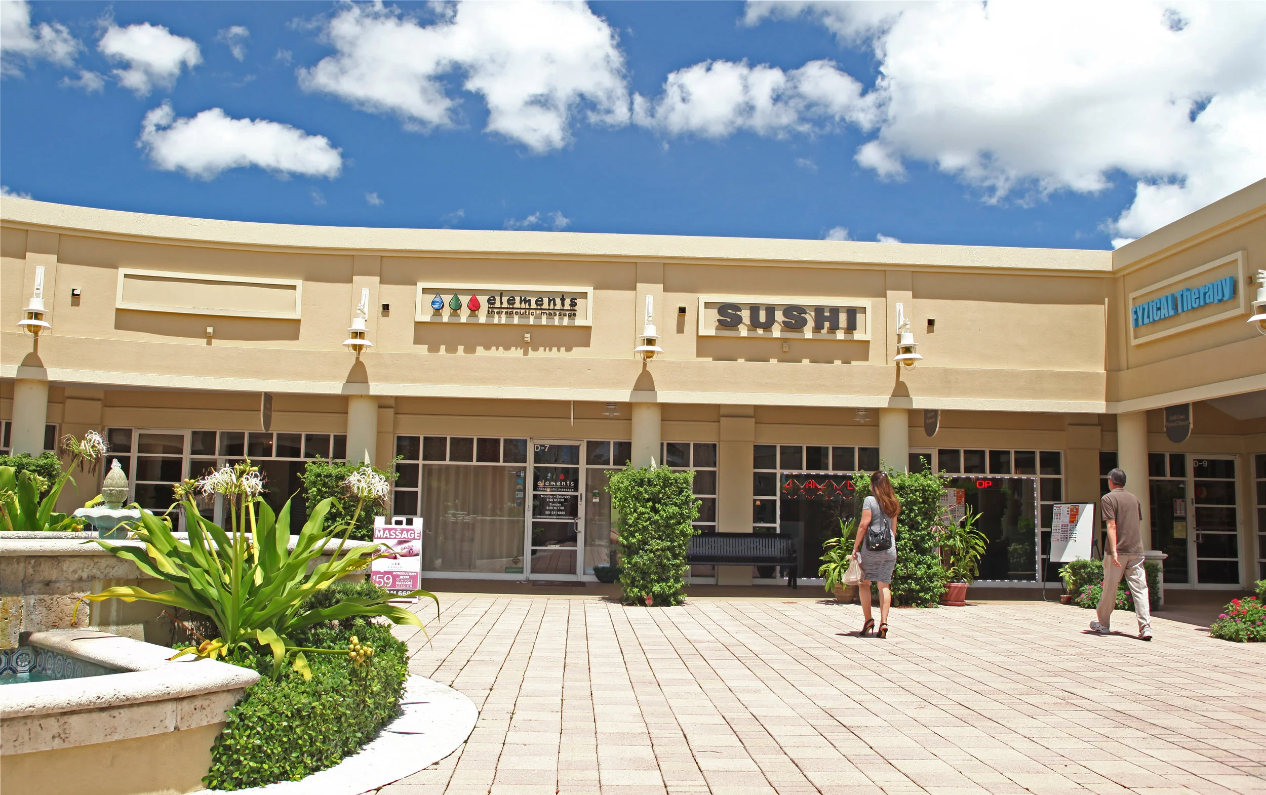 Exterior store image of elements massage, with A Frame promotional sign on the sidewalk out front of location.