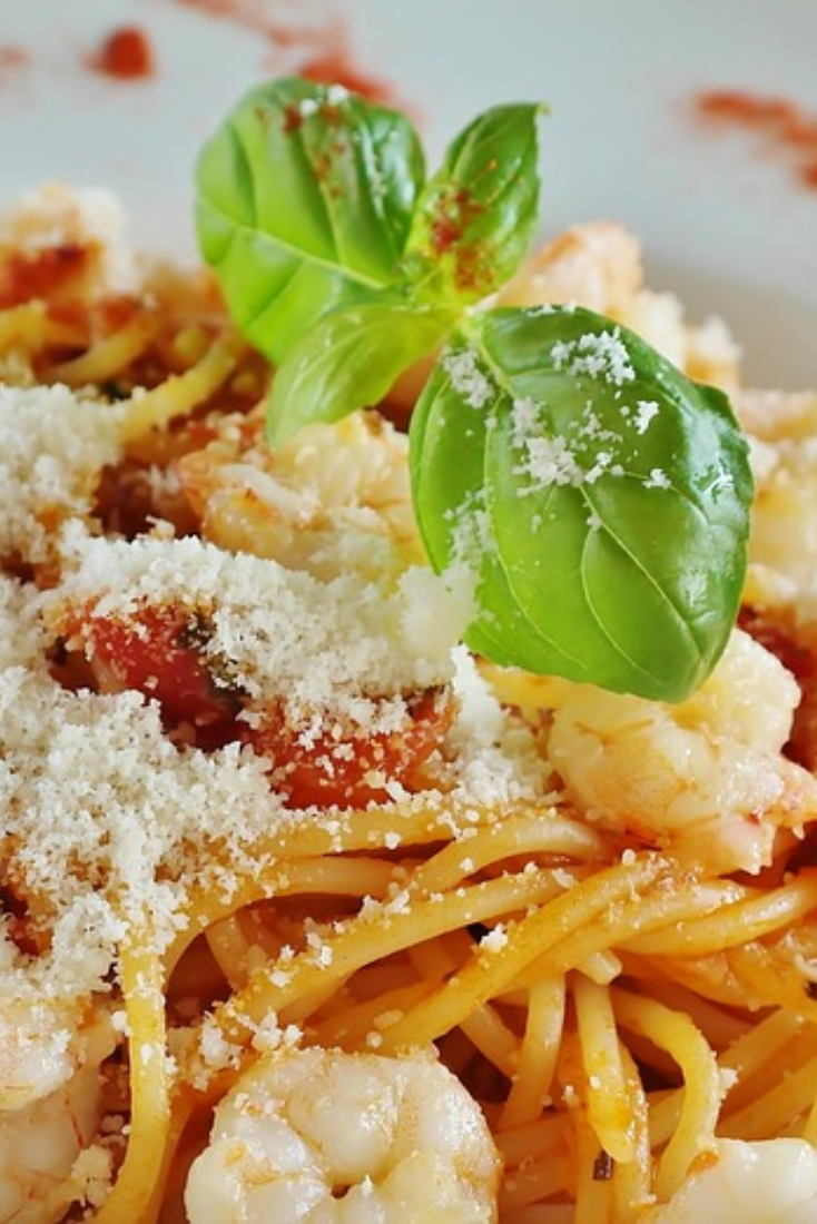 Close up image of plate of noodles with shrimp, topped with Parmesan cheese and parsley 