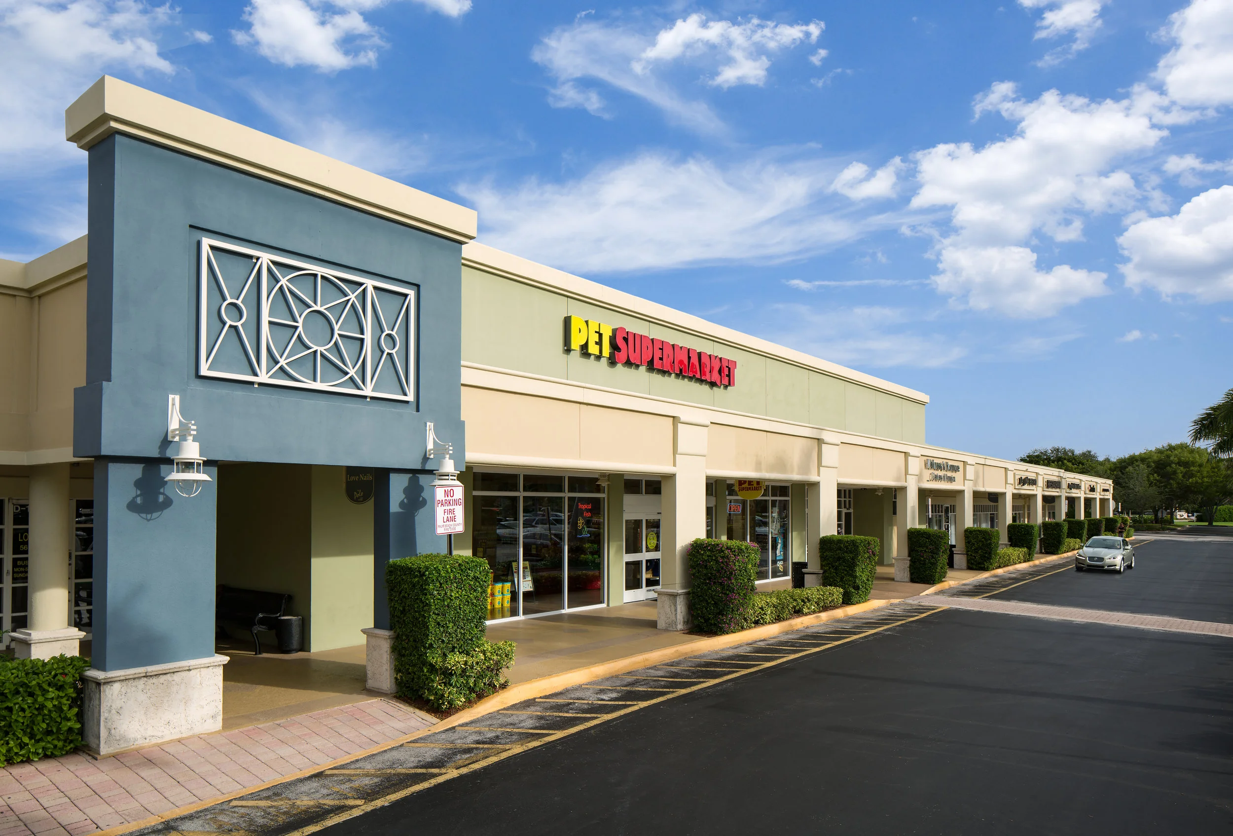Exterior shopping center image out front of Pet Supermarket showing their sign with the word pet in yellow letters and the work supermarket in red letters 