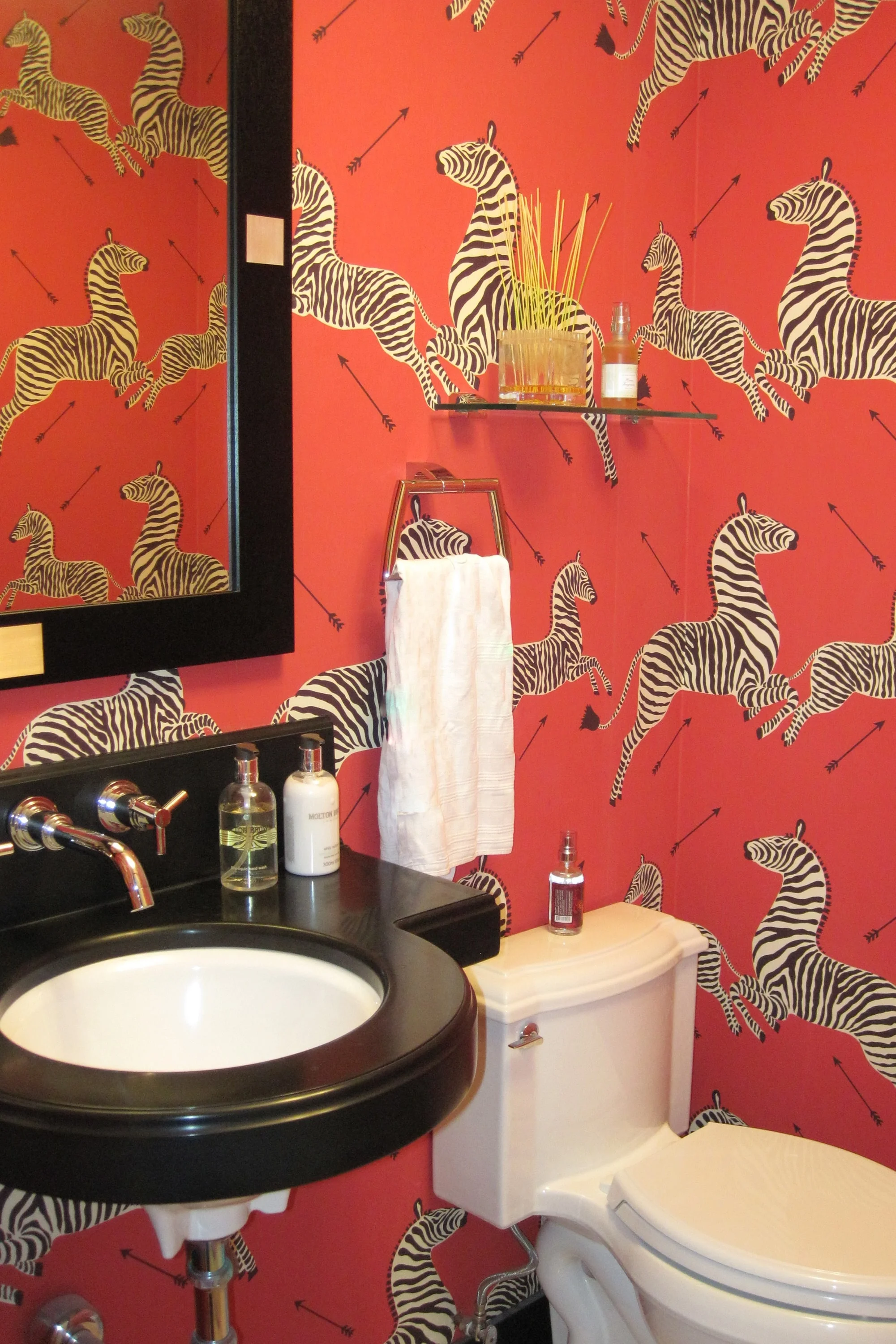 This powder room is a Modern Neo-Classic jewel box. The vibrant polished nickel accents, bold zebra wallpaper, and a custom floating vanity are elegant and whimsical.