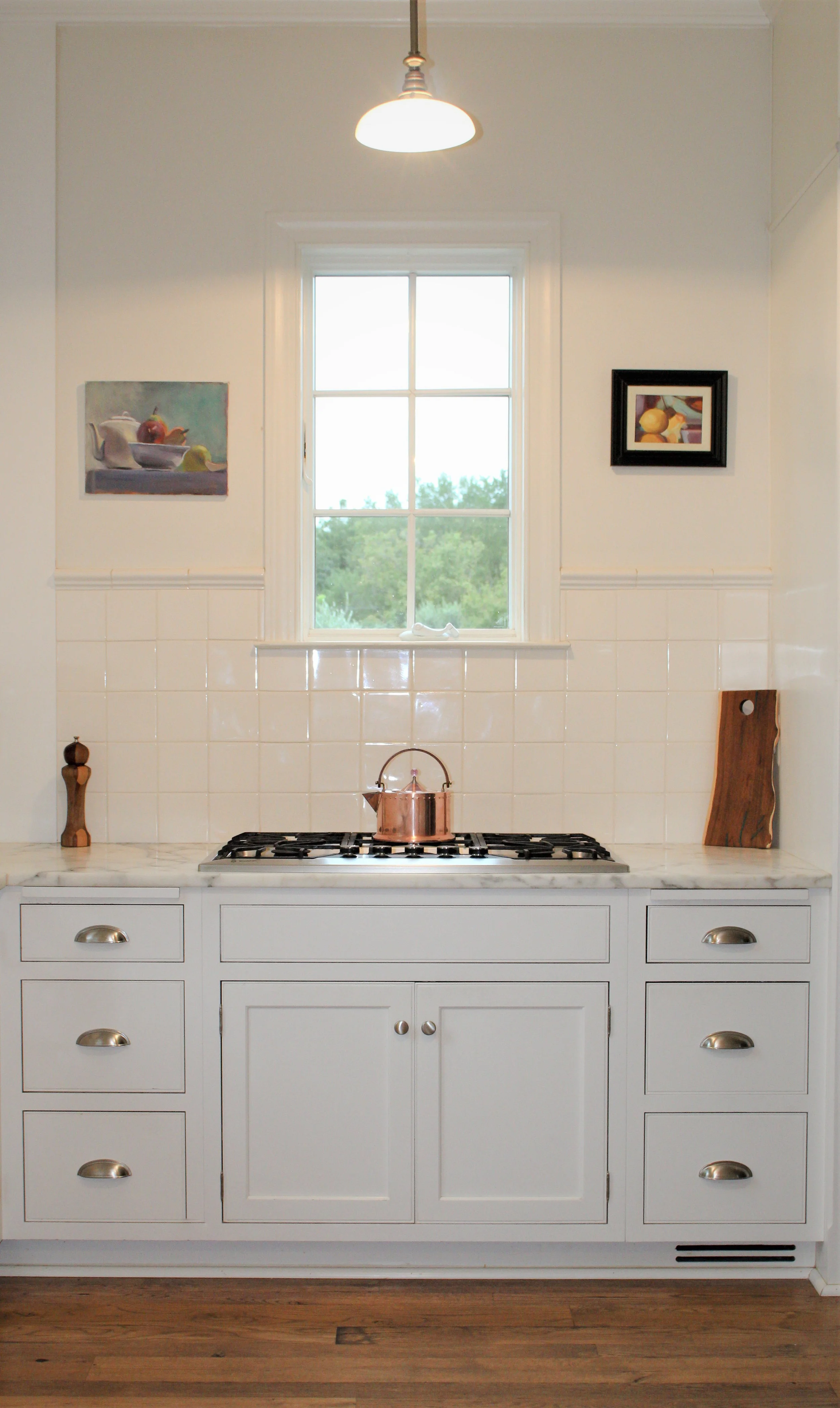 A classic white on white kitchen is warmed up with handmade tiles and reclaimed wood floors. Satin Nickel accessories and Calacatta Caldia countertop, give the kitchen a slightly contemporary feel.